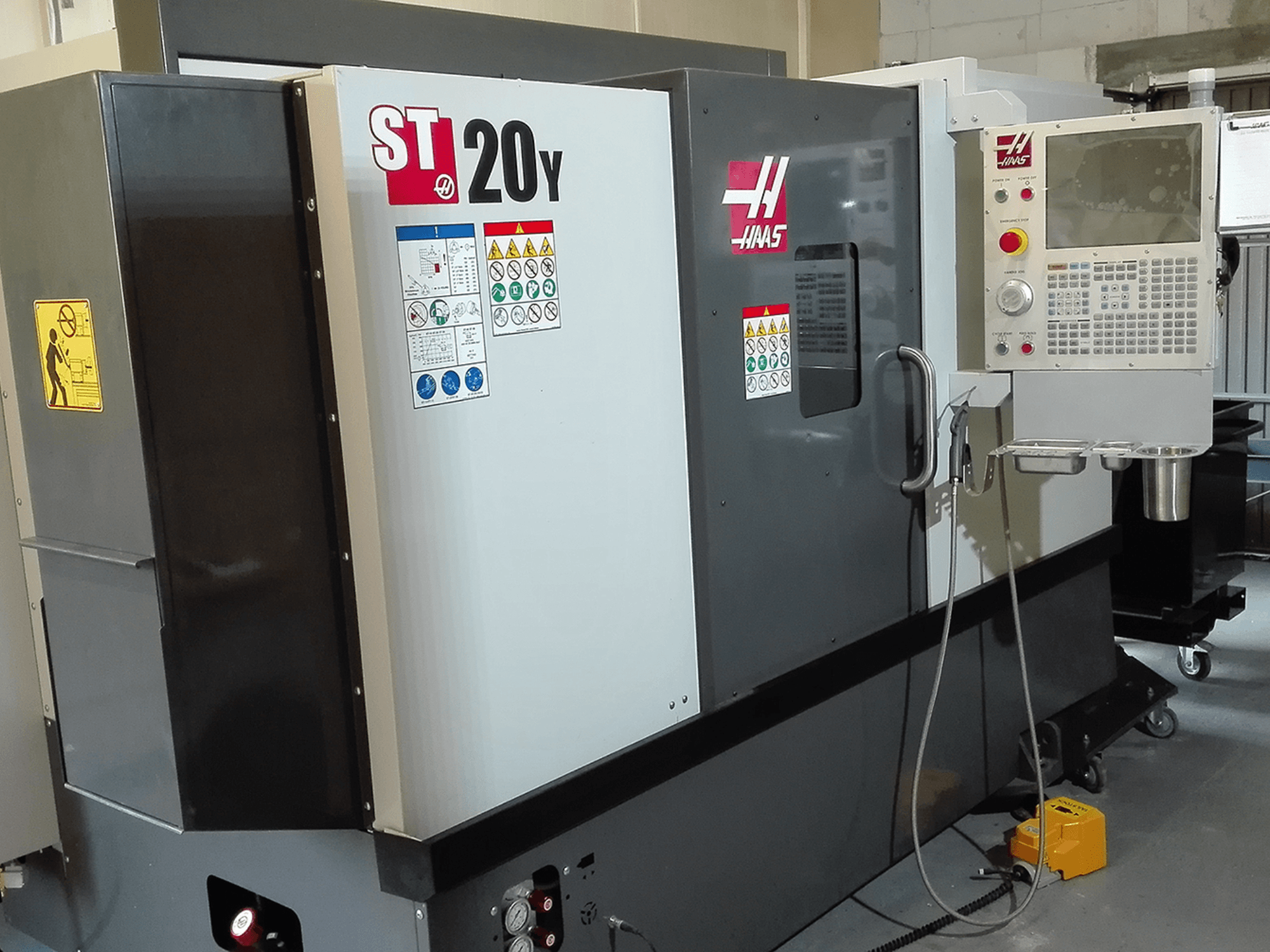 Tornio CNC Haas ST20Y in vista frontale, con pannello operativo, etichette di sicurezza e sistema di raffreddamento.