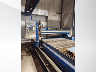Macchina da taglio CNC di PlasmaCam, vista frontale che mostra il pannello di controllo e il piano di taglio in metallo con doghe.