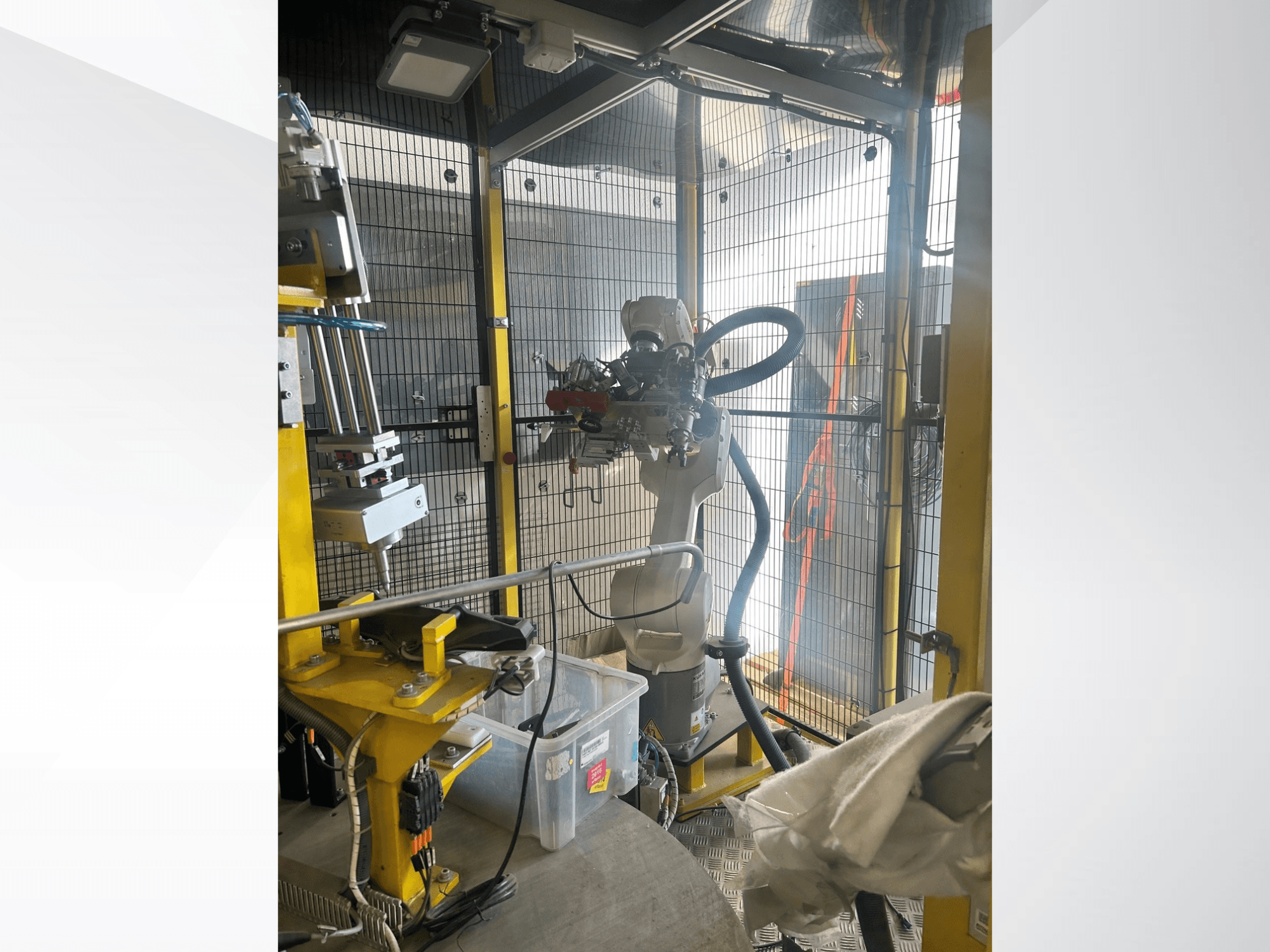 Braccio robotico del sistema di automazione automobilistica MEI all’interno di un involucro protetto, vista frontale, con componenti meccanici e comandi.