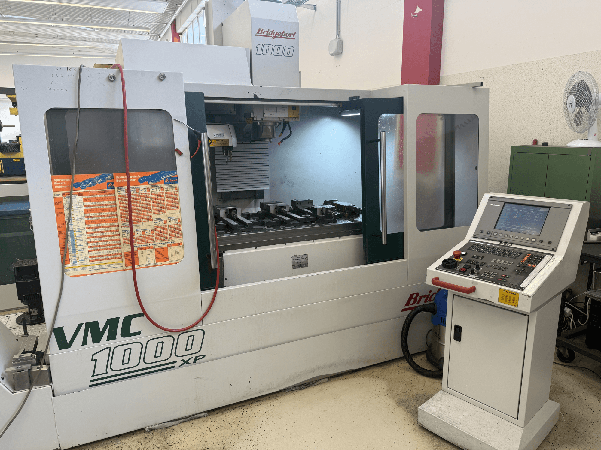 Vista frontale del centro di lavorazione verticale Bridgeport VMC 1000 XP, con i comandi, l'area di lavoro e gli attacchi degli utensili.