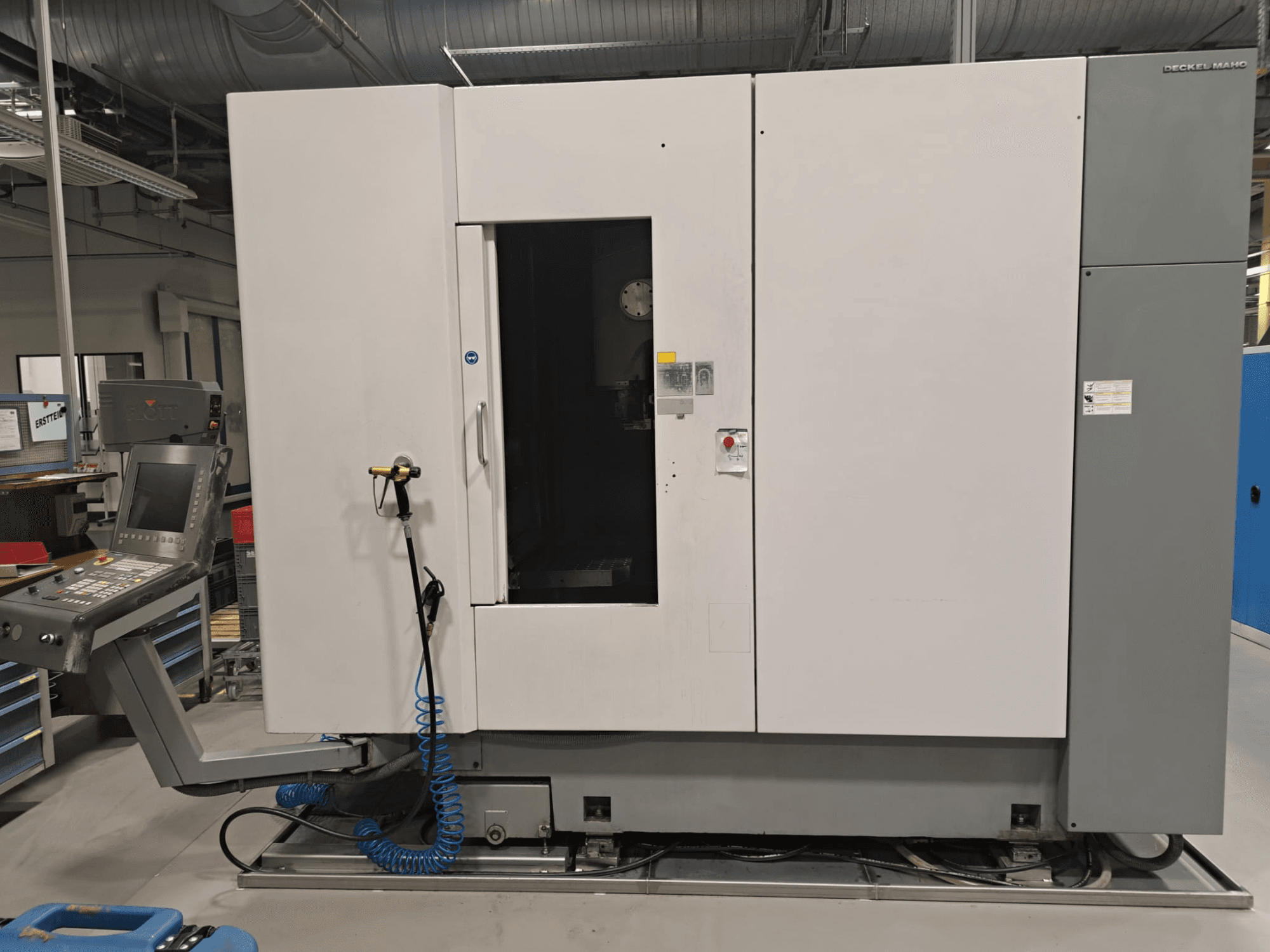 Centro di lavorazione verticale DECKEL MAHO DMP 60V, vista frontale che mostra il pannello di controllo e il corpo principale con lo sportello aperto per consentire l'accesso.