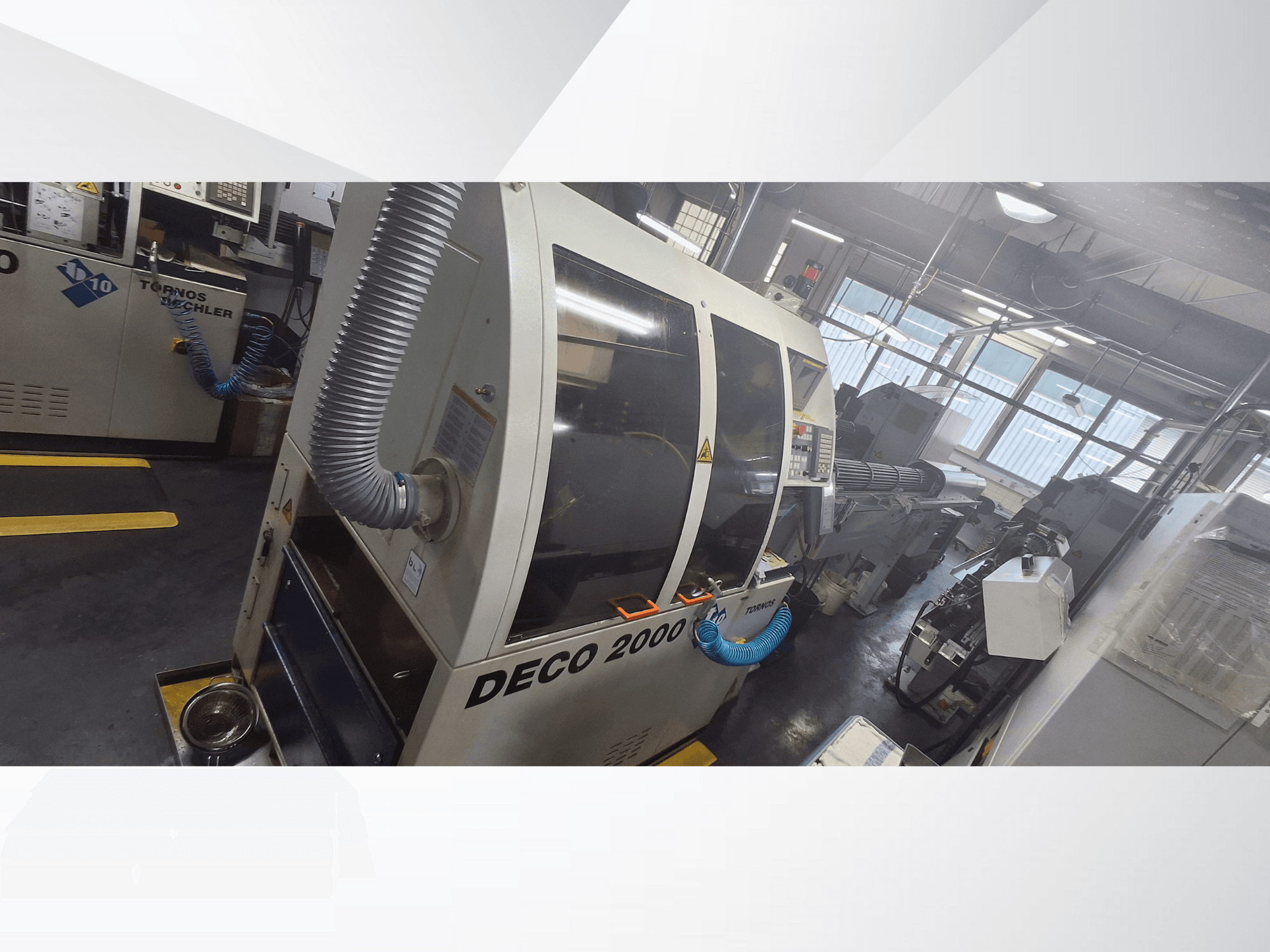 Macchina DECO 2000 CNC in officina, vista frontale, con tubo di ventilazione e pannello di controllo, progettata per lavorazioni di precisione.