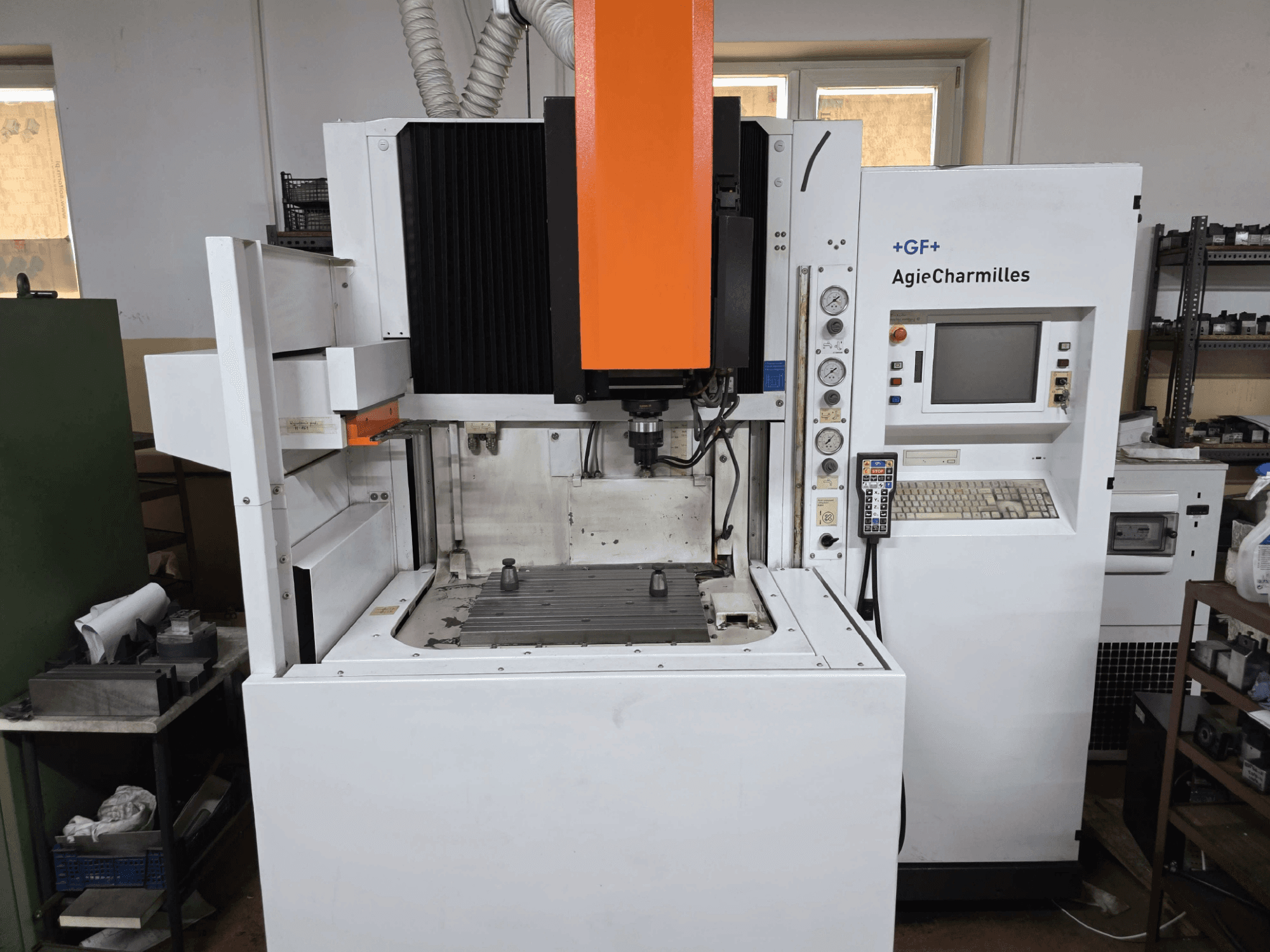 Macchina CNC GF AgieCharmilles, vista frontale con mandrino arancione in evidenza, pannello di controllo digitale e tavola di foratura montata.