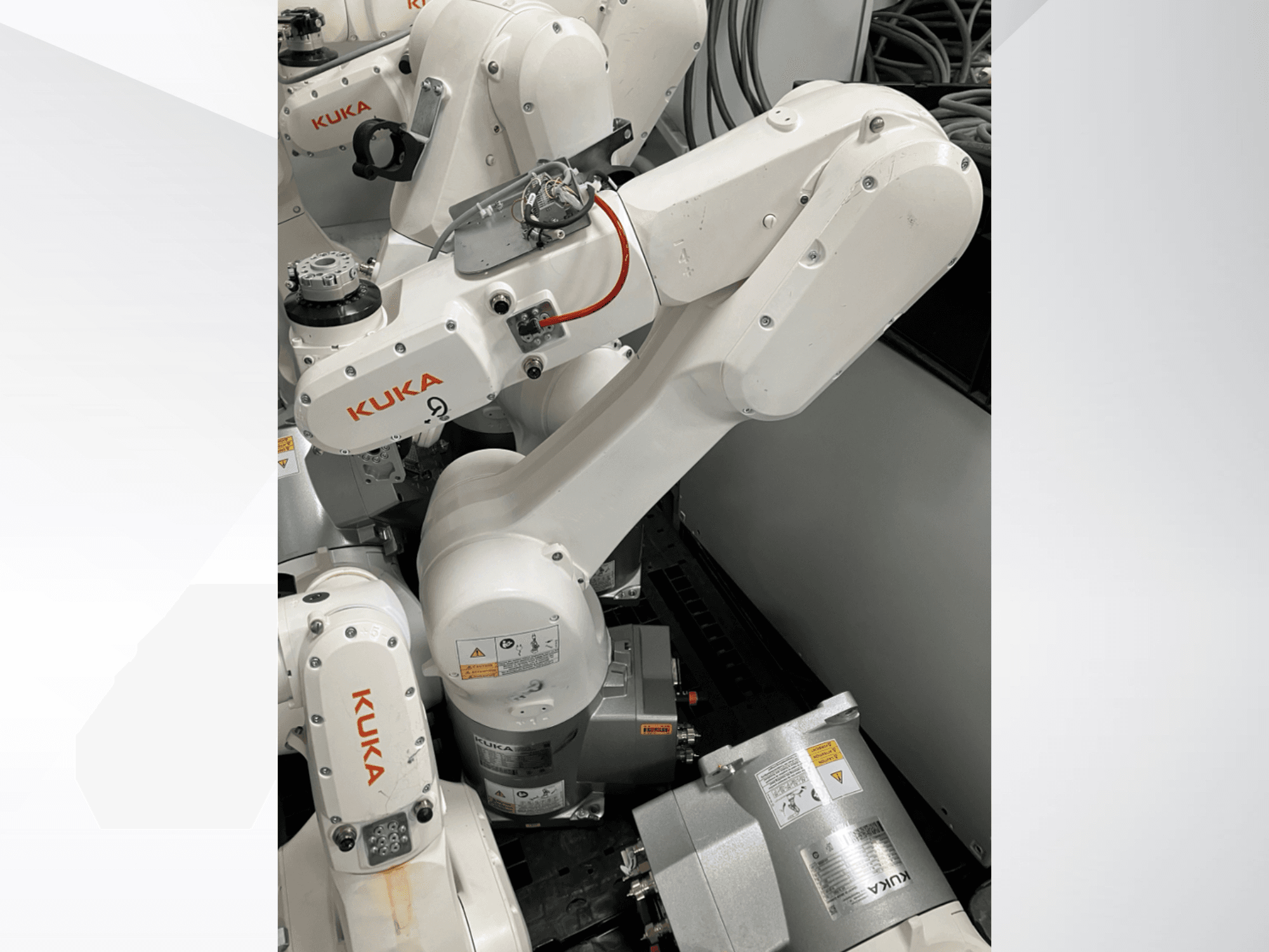 Braccio robotico KUKA KR 6 R900 CR, vista laterale; presenta motori e connettori visibili, avvertenze di sicurezza etichettate e bracci meccanici.