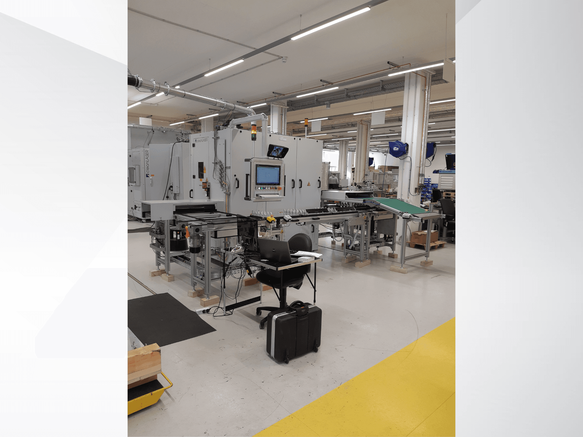 Macchina utensile CLEAN LASER clean CELL 3220, vista frontale con pannello di controllo, trasportatore e postazione di lavoro in un ambiente industriale.