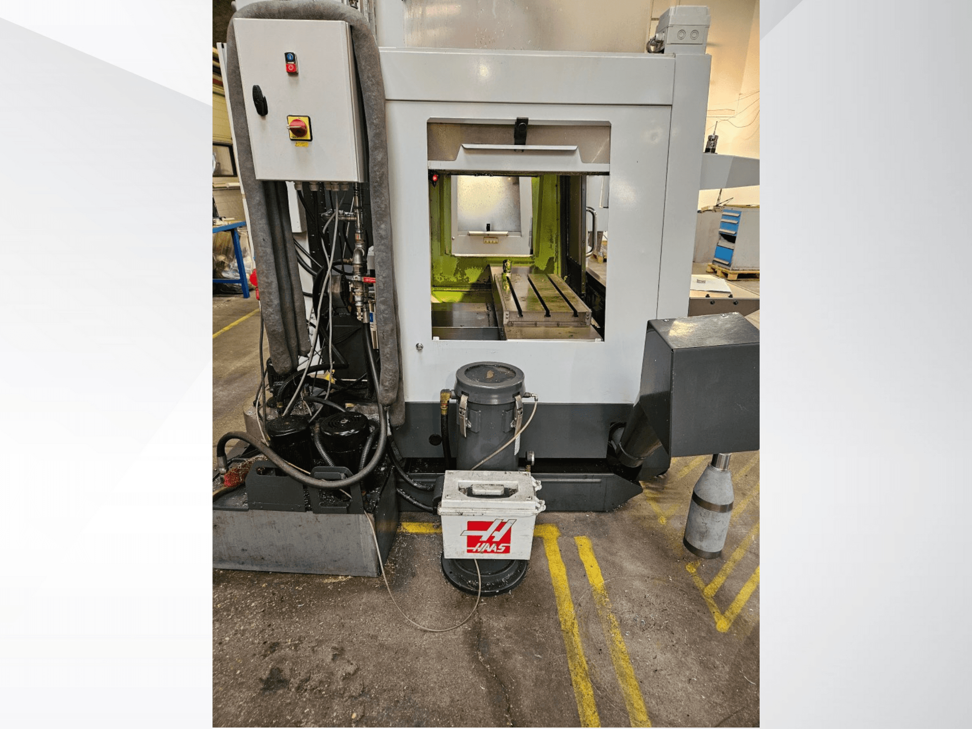Vista frontale della macchina CNC Haas che mostra il pannello di controllo, il serbatoio del refrigerante e il letto lavorato.