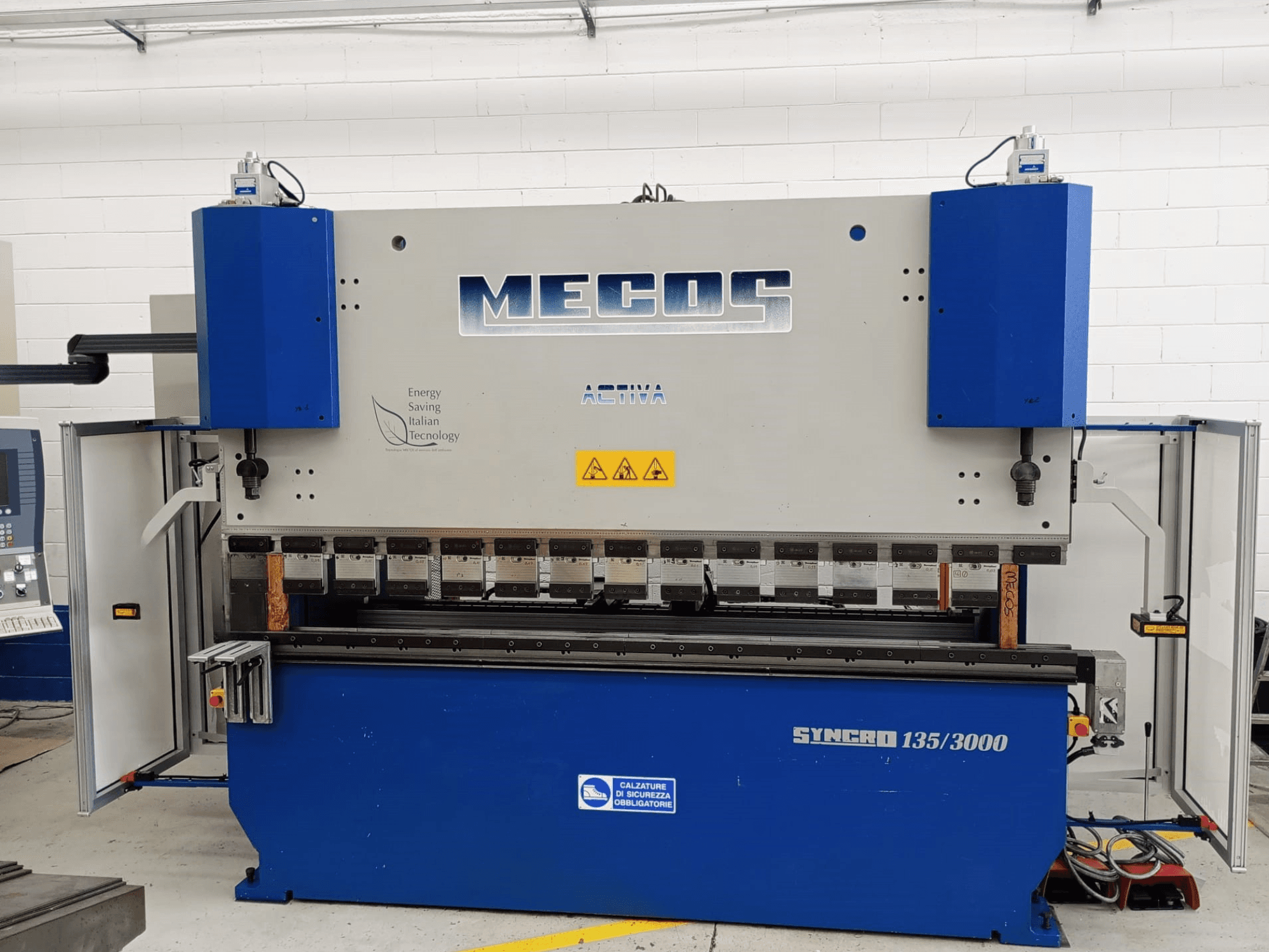 Vista frontale della pressa piegatrice MECOS SYNCRO 135/3000, che mostra i comandi, gli strumenti di piegatura e le caratteristiche di sicurezza.