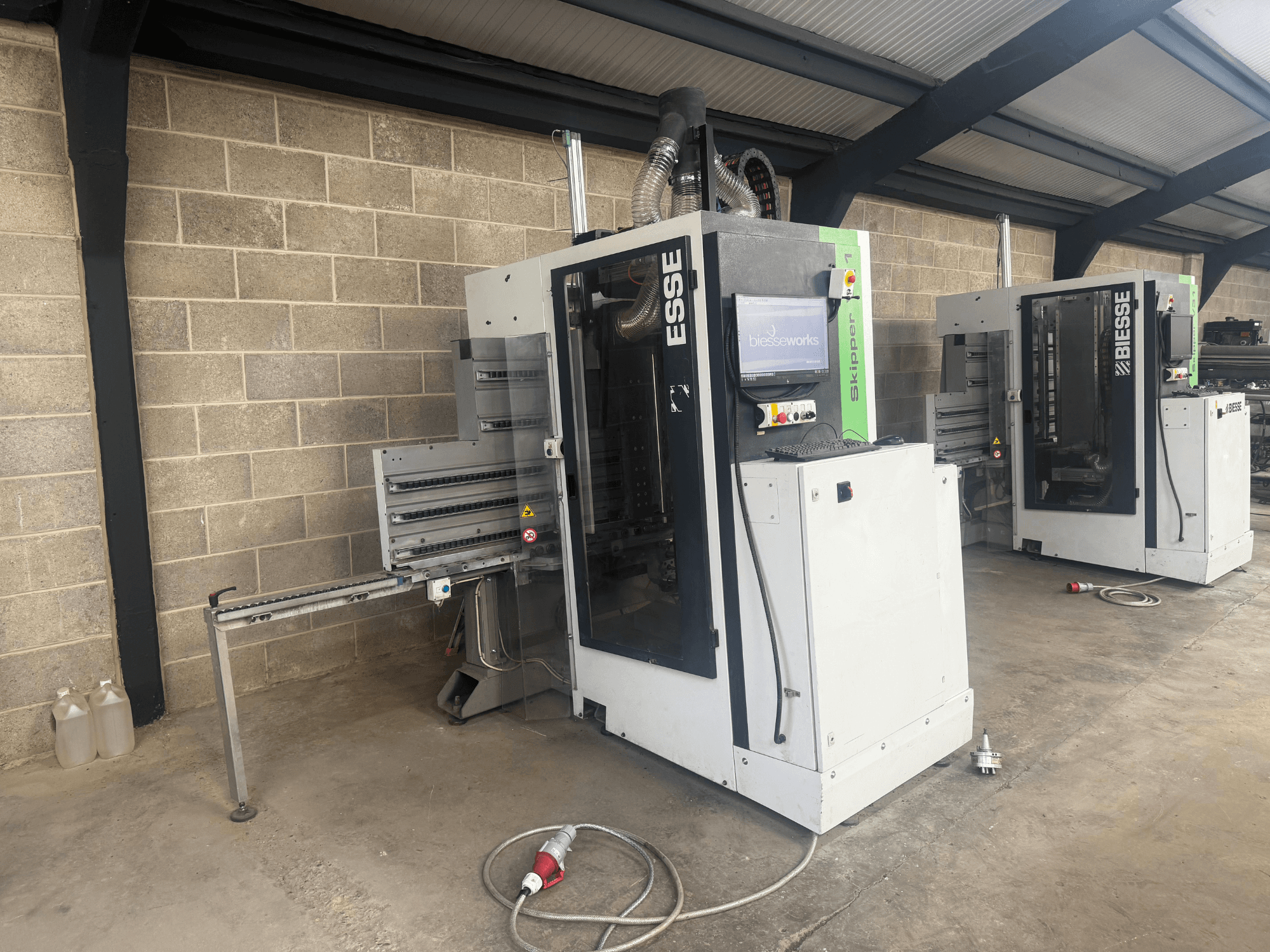 Alesatrice per legno BIESSE Skipper v31 in vista laterale, con pannello di controllo e macchinari adiacenti, in un'officina.