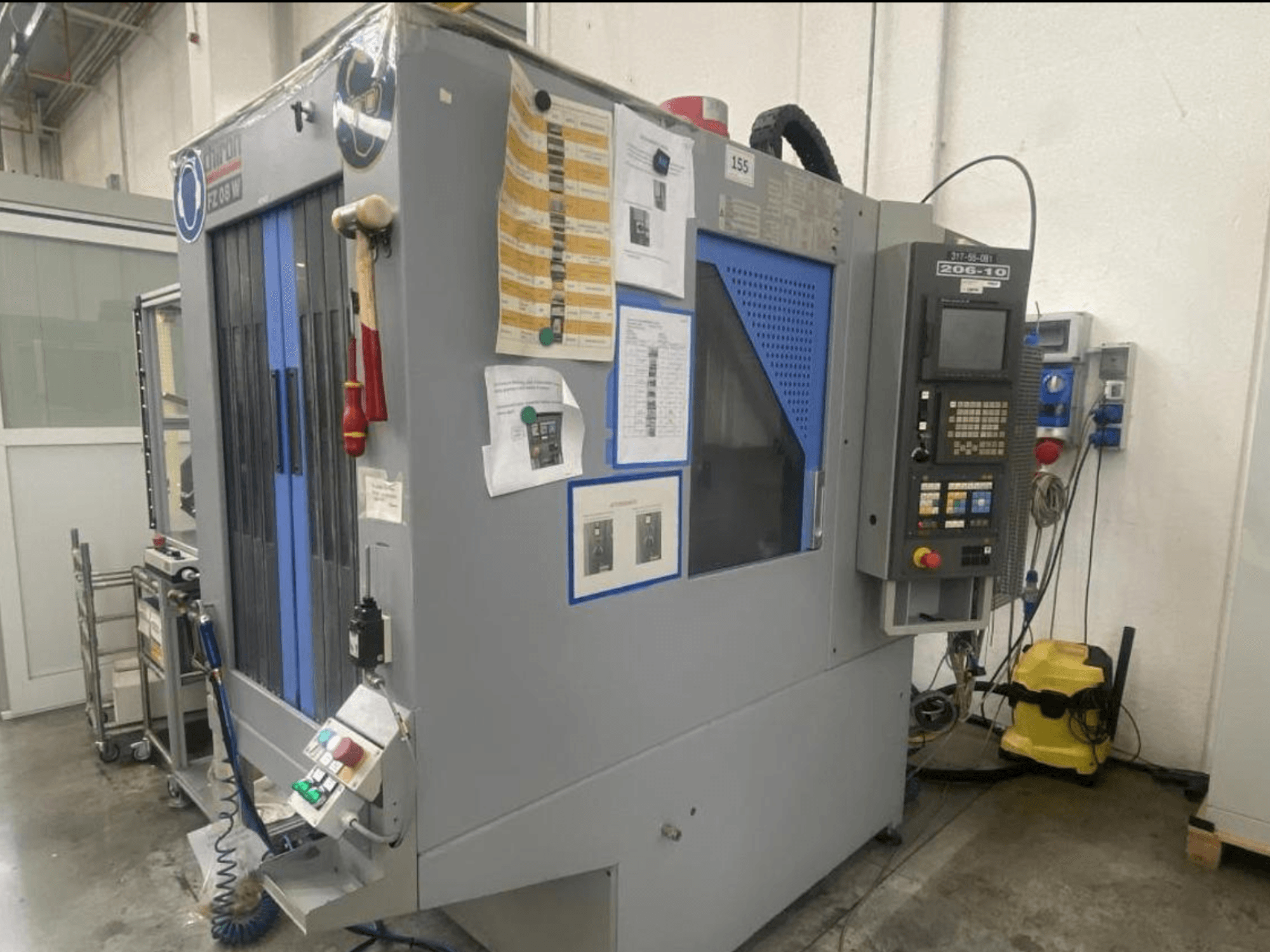 Macchina CNC di Shin Lin, vista frontale, con pannello di controllo, pulsanti operativi e istruzioni di sicurezza allegate.