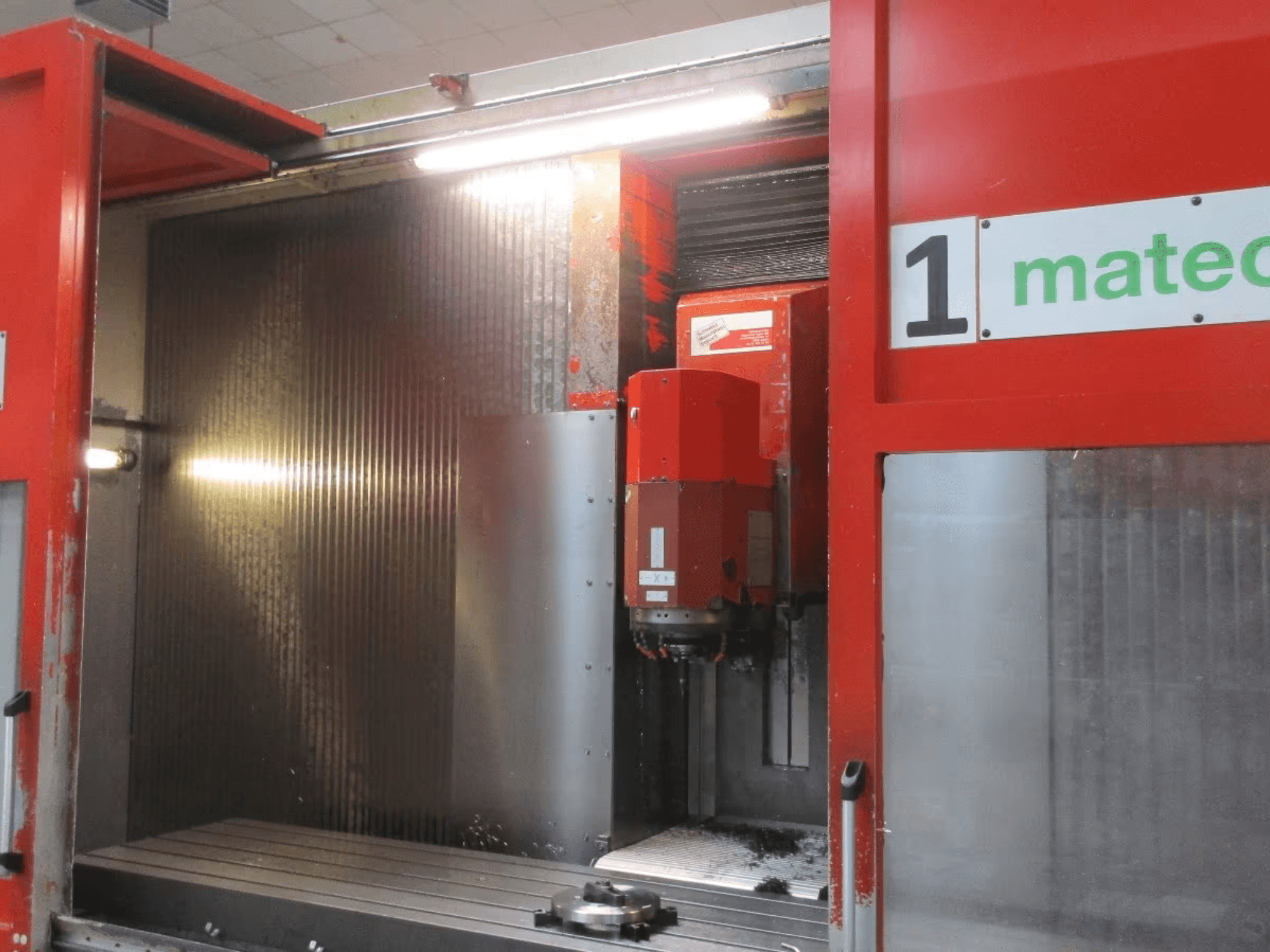 Vista frontale del Centro di lavoro verticale CNC Matec 30 HV con utensile da taglio visibile, superficie metallica e dettagli interni della macchina.