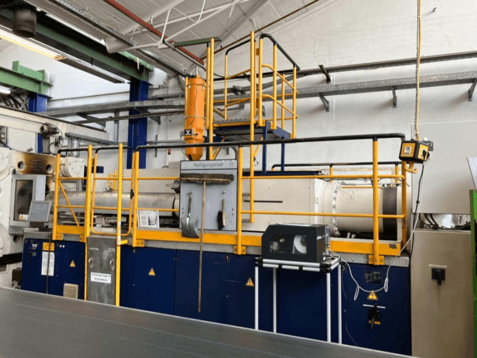 Macchina ad iniezione idraulica Krauss Maffei 1000-8000 M, vista laterale con ringhiera di sicurezza e pannello di controllo visibili.