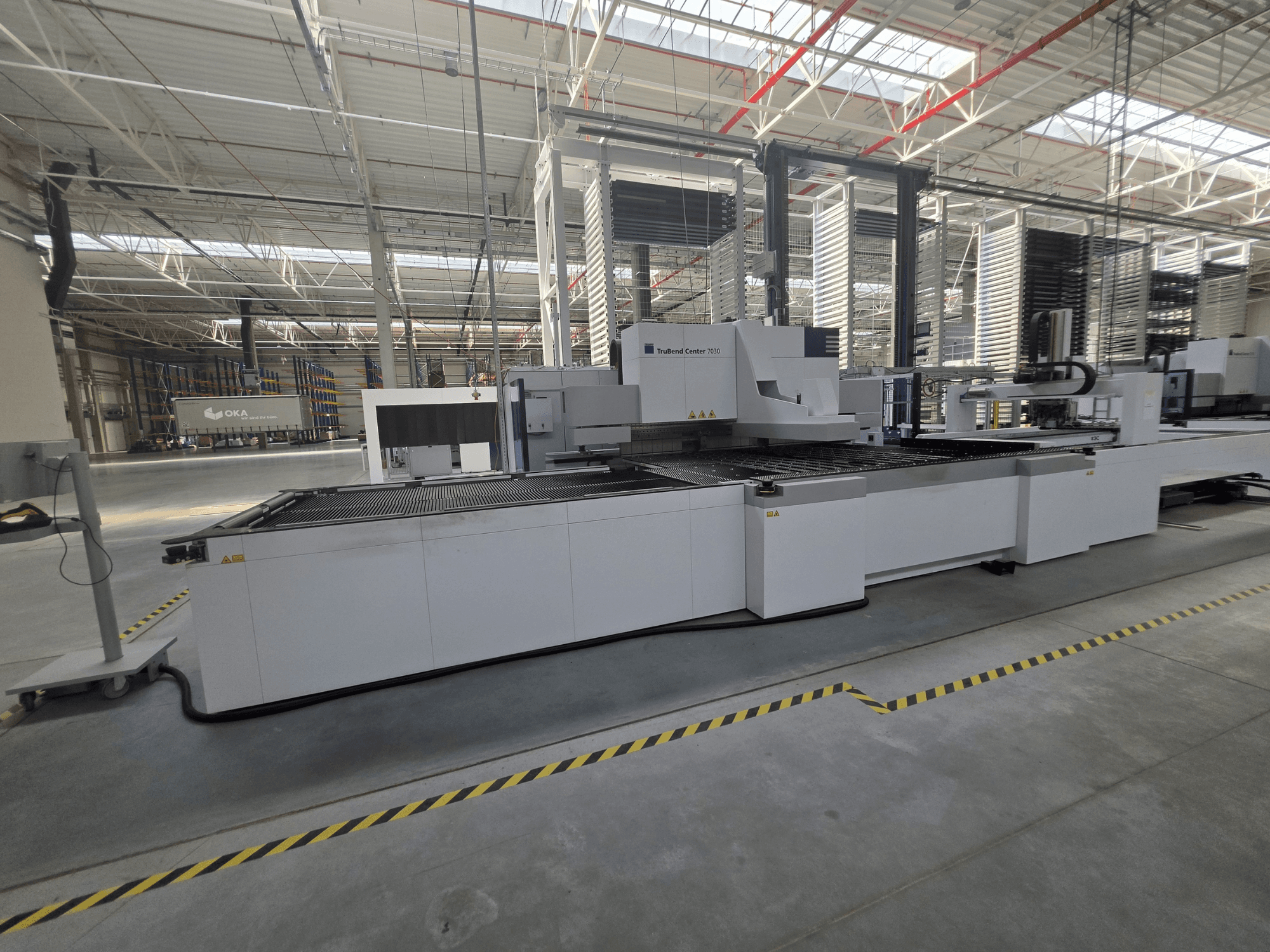 Piegatrice TRUMPF TruBend Center 7030, vista laterale, che mostra l'area di lavoro e i comandi in un'ampia officina.
