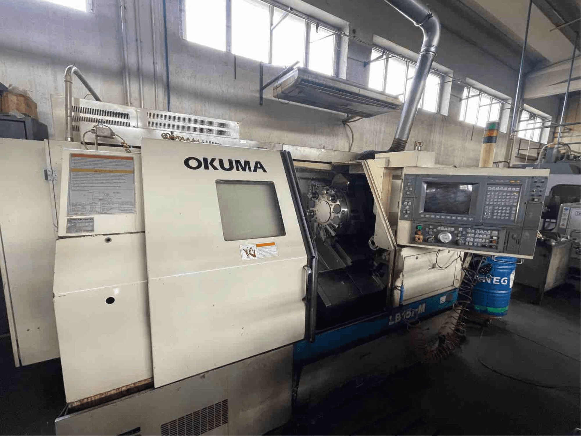 Tornio orizzontale Okuma LB15i-M, vista frontale; presenta il pannello di controllo e l'area degli utensili da taglio con indicatori dettagliati.