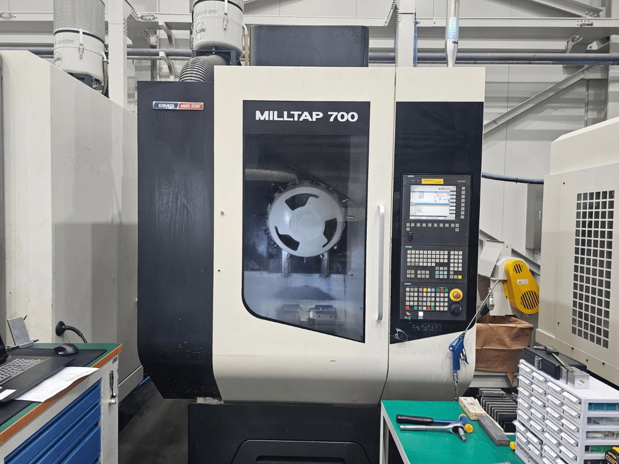 Centro di lavorazione verticale DMG MORI MILLTAP 700, vista frontale, con dettagli del pannello di controllo, del mandrino e dell'area di lavoro.