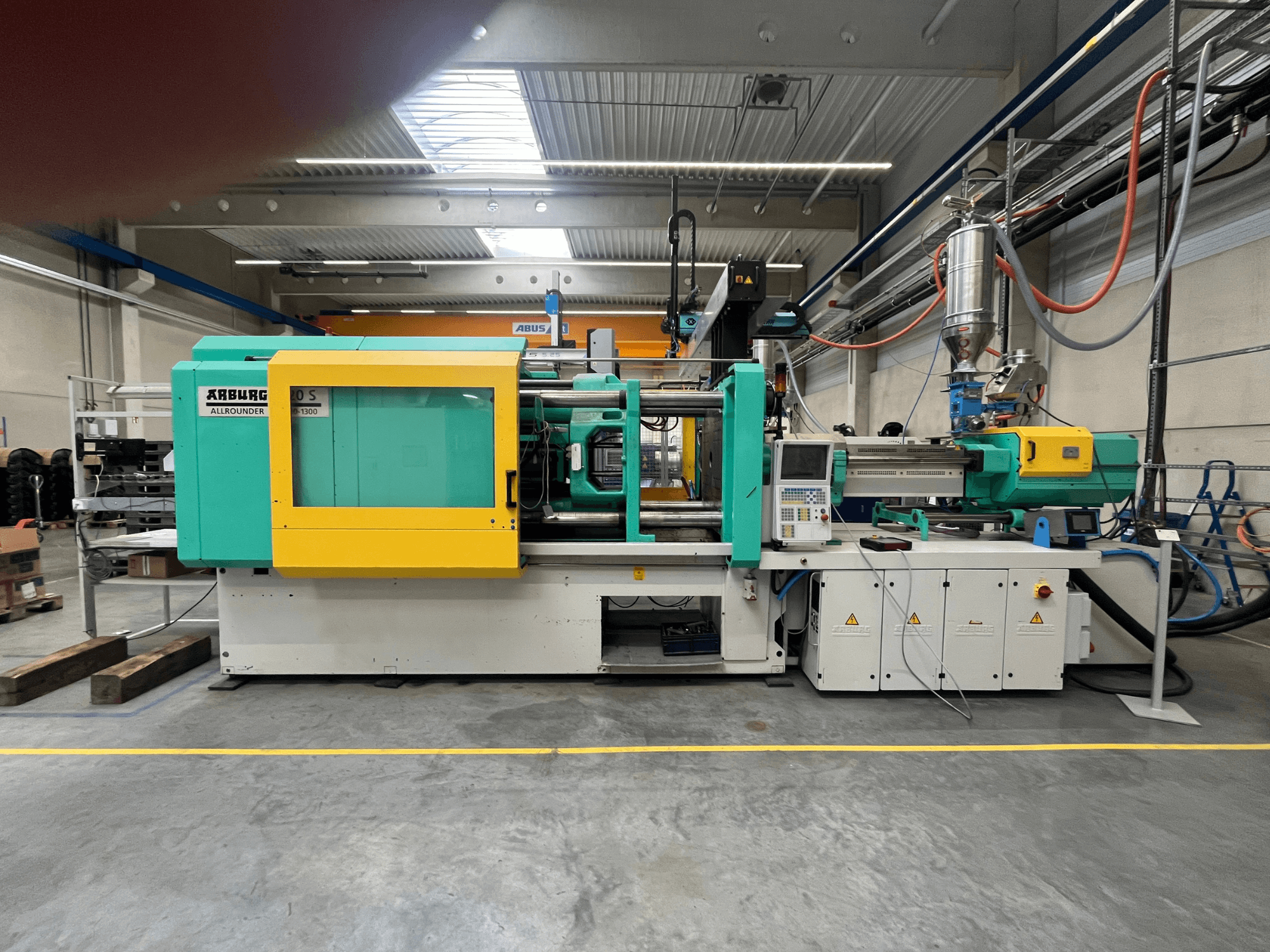 Pressa ad iniezione ARBURG Allrounder 370S, vista laterale, con involucro verde e giallo, interfaccia di controllo visibile.