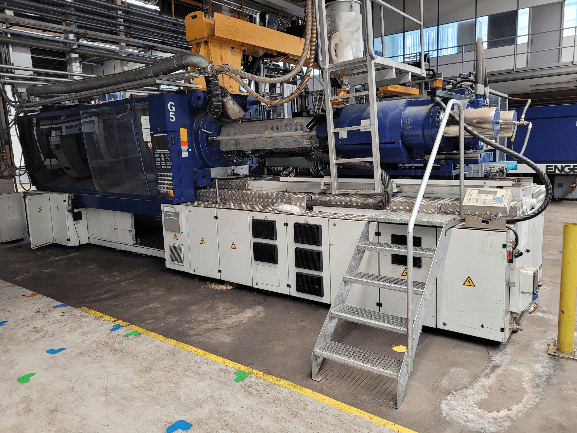 Macchina per lo stampaggio a iniezione G5, vista laterale, con pannello di controllo, scaletta e piano di lavoro in acciaio inox visibili.