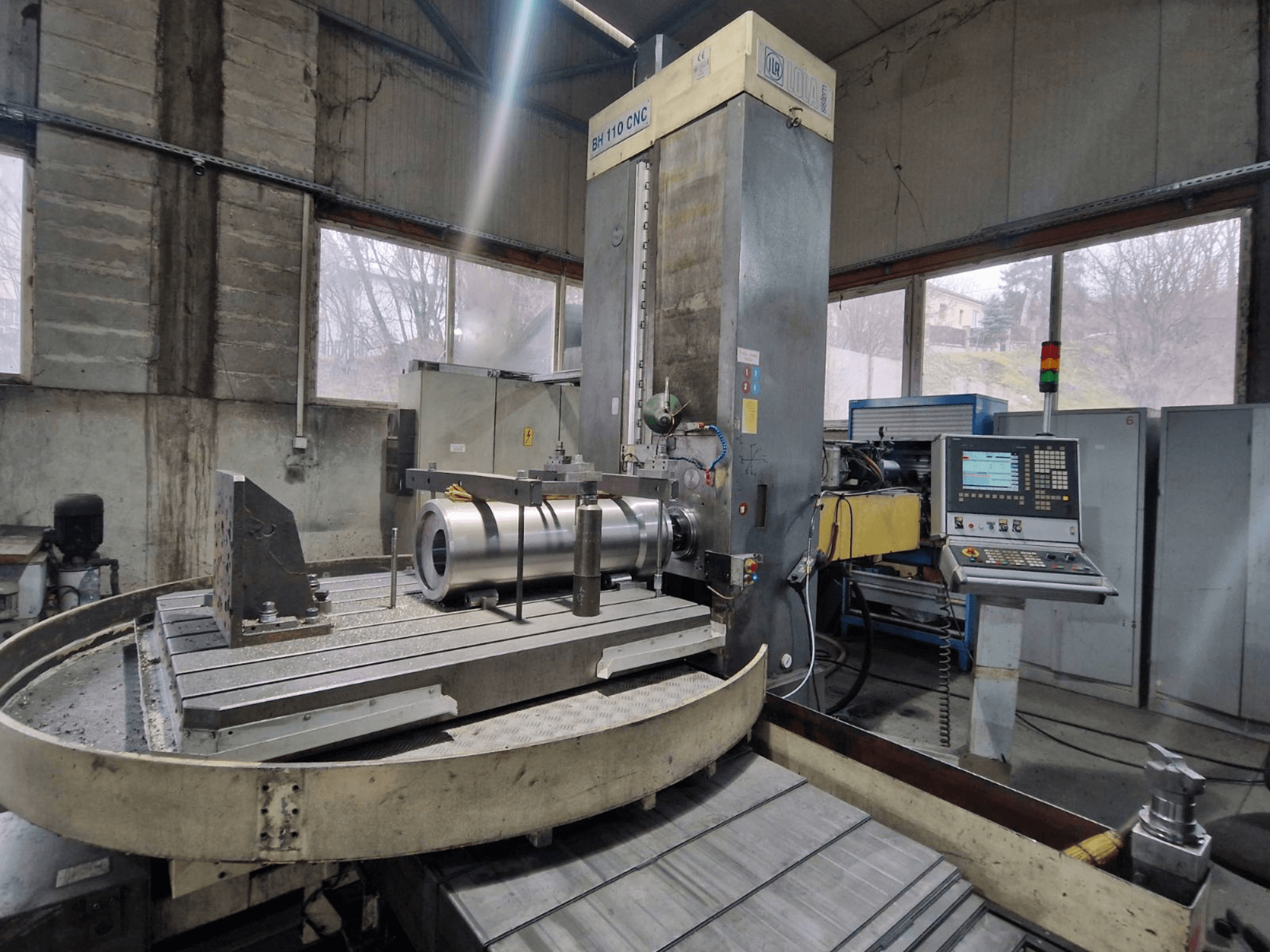 Alesatrice CNC LOLA BH 110 in un'officina, vista frontale, con pezzo in metallo e pannello di controllo.