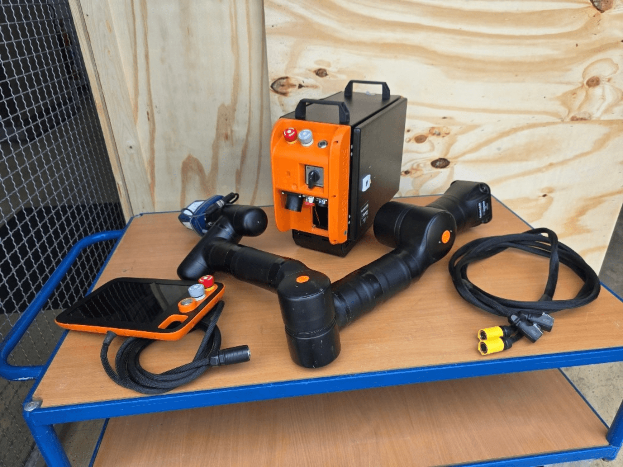 Robot collaborativo KASSOW ROBOTS KR810, vista frontale, con controller, cavi e connettori su un tavolo di legno.
