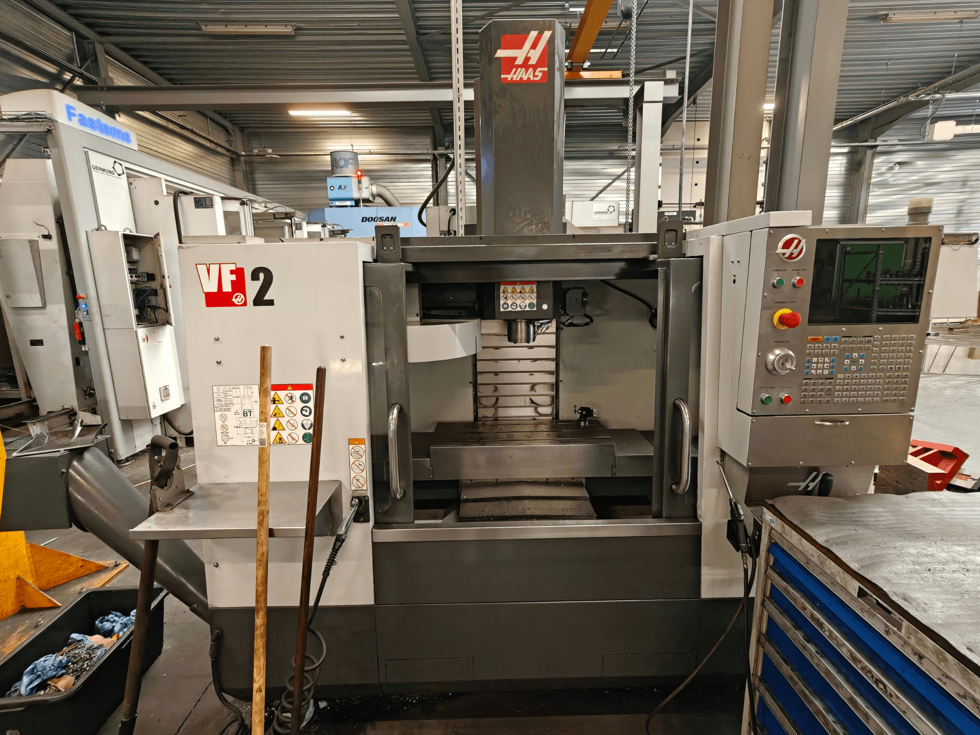 Centro di lavorazione verticale HAAS VF-2, vista frontale, che mostra i comandi, il mandrino e il piano di lavoro in un ambiente di officina.