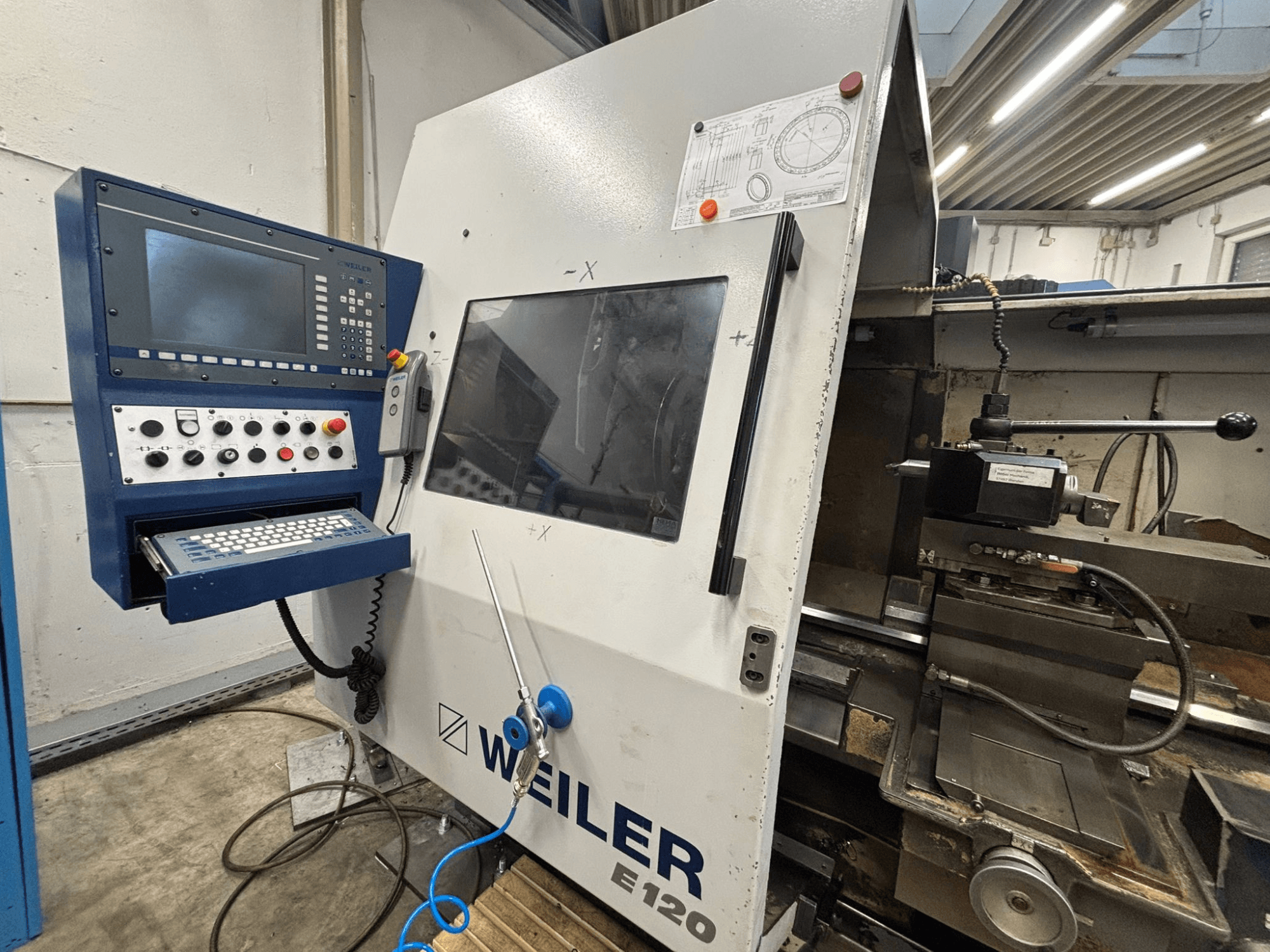Pannello di controllo e interfaccia della macchina CNC Weiler E-120, vista frontale con pulsanti visibili, schermo e componenti operativi.