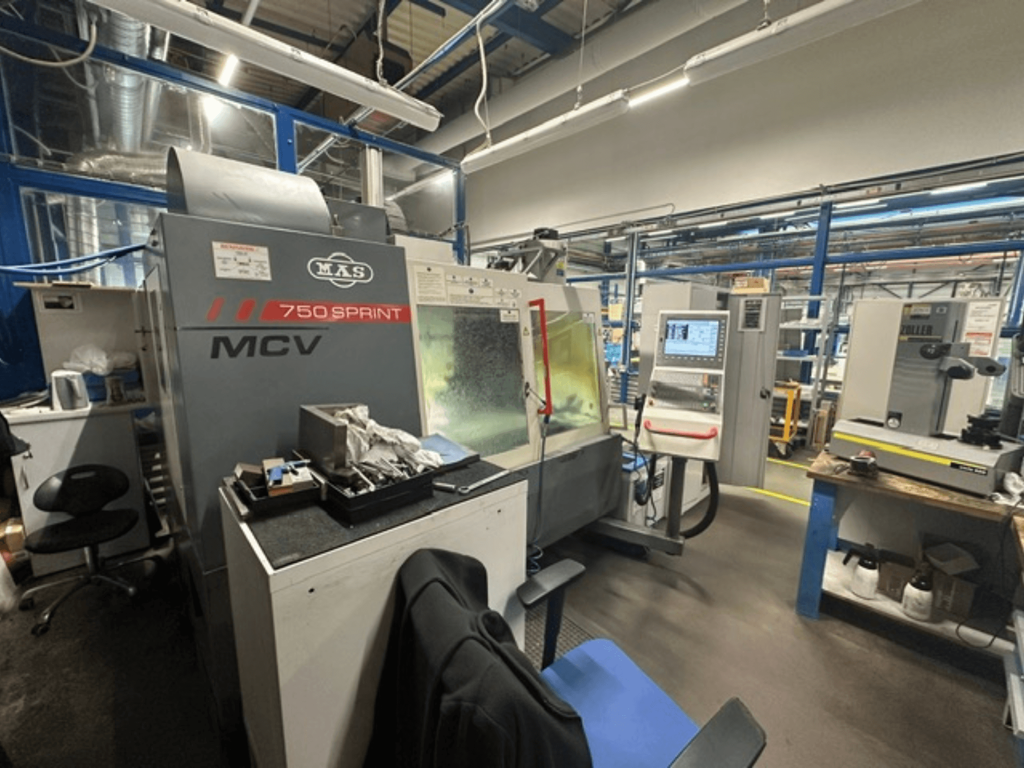 Centro di lavorazione verticale KOVOSVIT MAS MCV 750 Sprint in un'officina, con vista laterale del pannello di controllo e dell'area di lavoro.