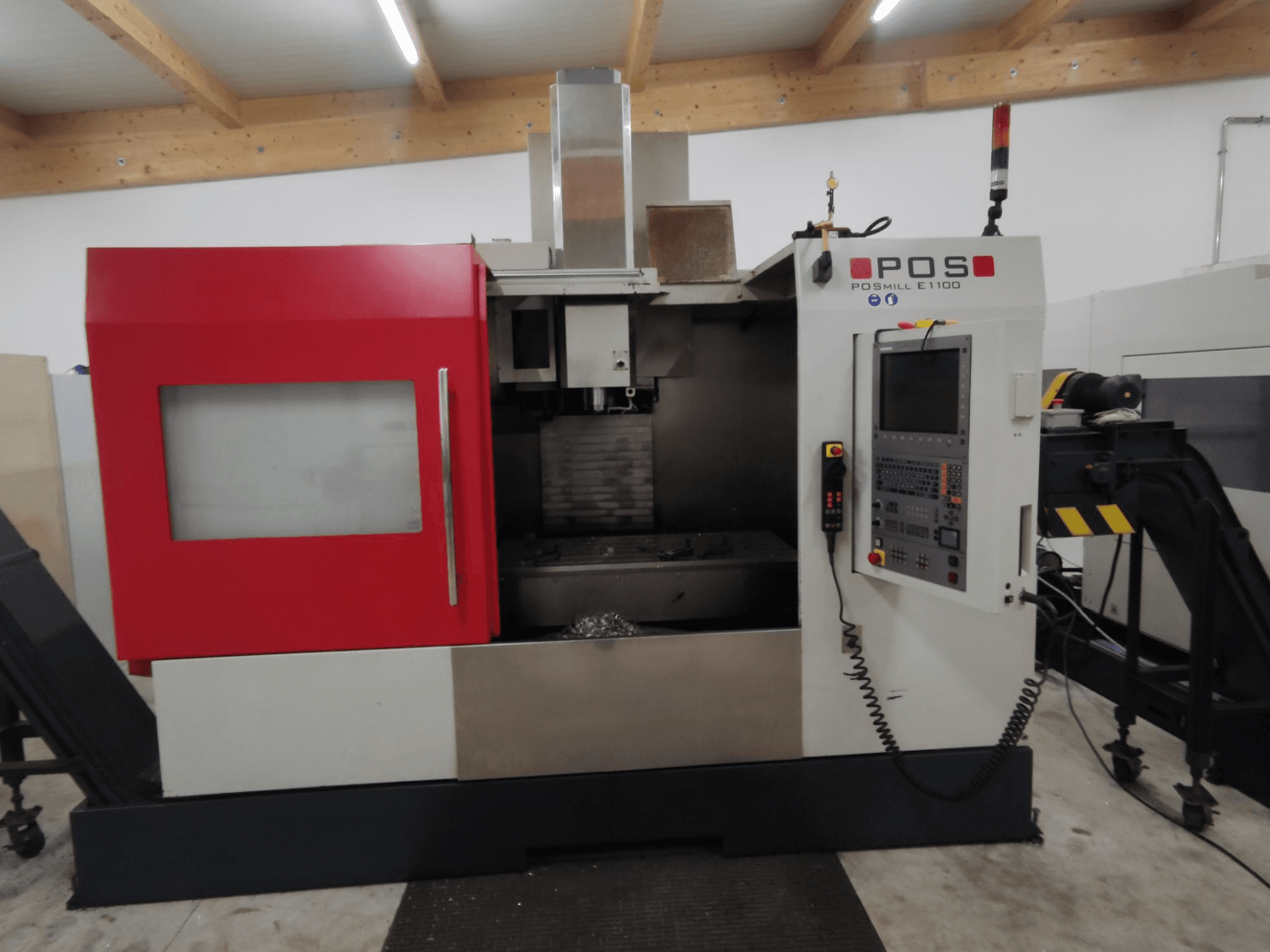 Fresatrice a controllo numerico POSMILL E1100 in vista frontale con involucro rosso, pannello di controllo e luce di sicurezza sulla parte superiore.
