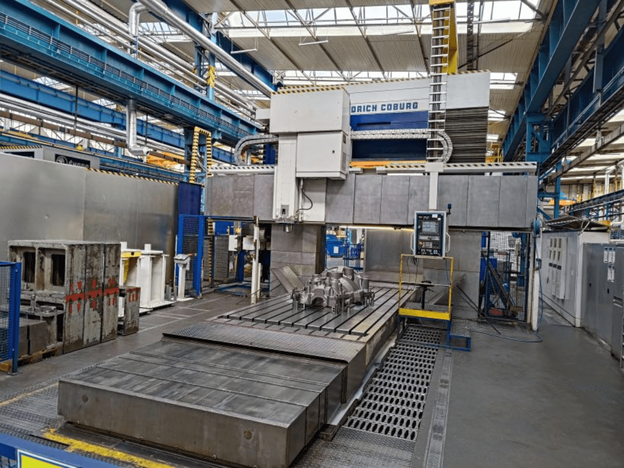 Fresatrice a portale WALDRICH COBURG 17-10 FP NC/5 in uno stabilimento, vista frontale, con grande tavolo di lavoro e pannello di controllo.