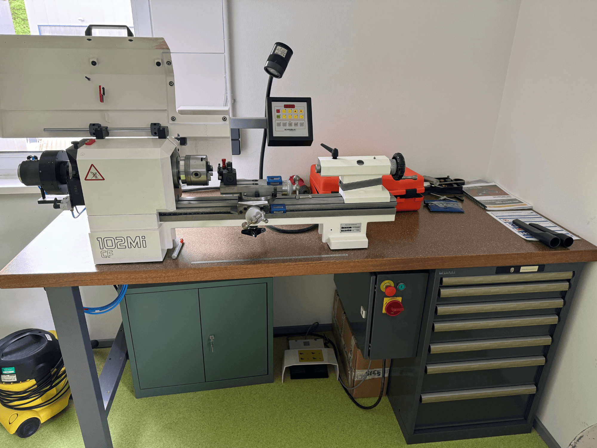 Tornio orizzontale SCHAUBLIN 102Mi W25 in un'officina, vista frontale con dettagli del pannello di controllo e del banco di lavoro.