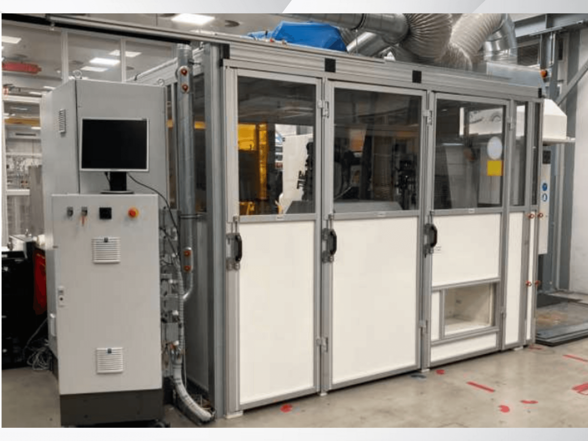 Macchina industriale con pannello di controllo, vista frontale; presenta porte in vetro, condotti di ventilazione e cablaggio a vista.