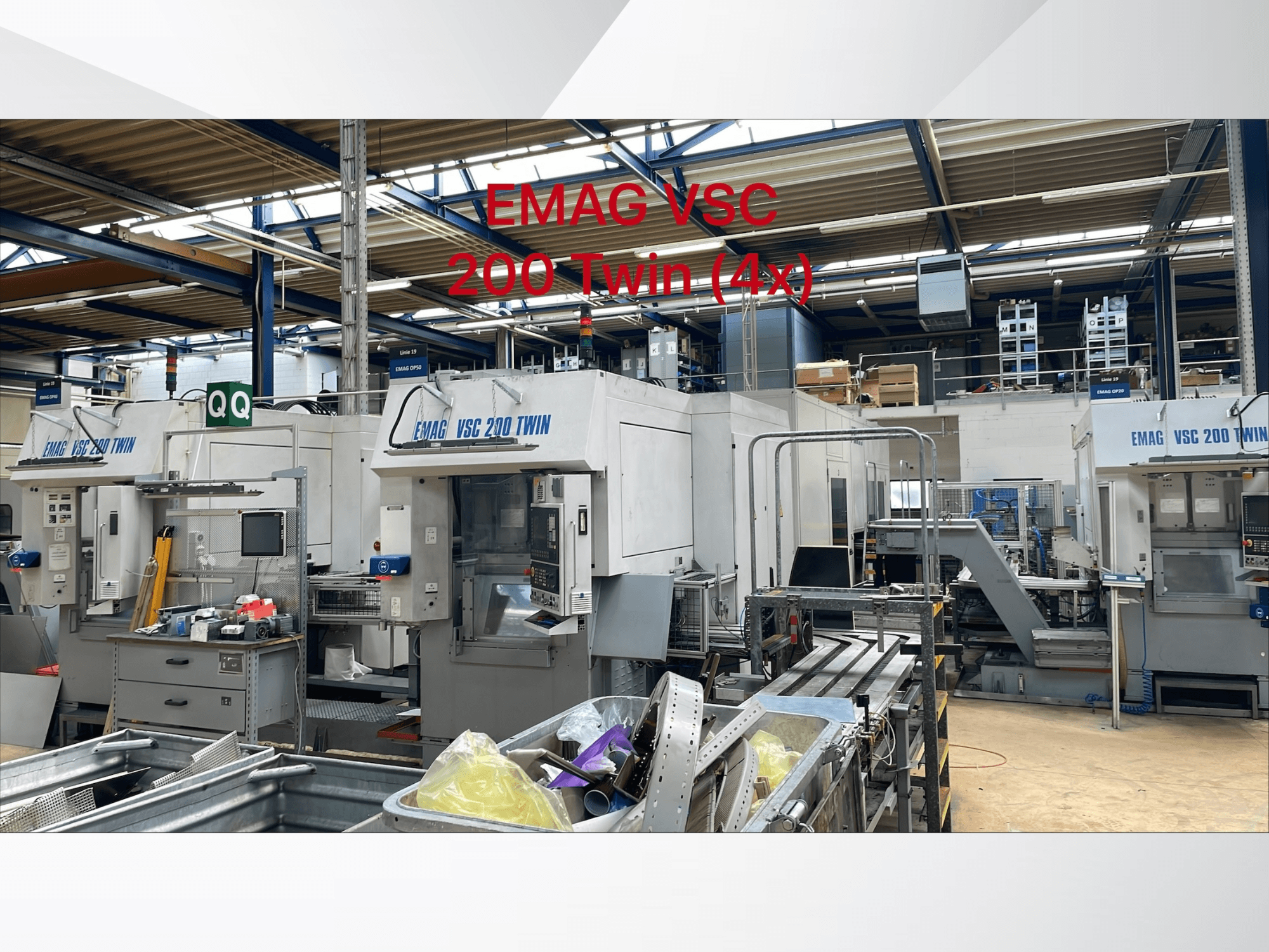 Vista frontale dei torni verticali EMAG VSC 200 TWIN OP 20 in un'officina, che mostra le unità multiple e le attrezzature circostanti.