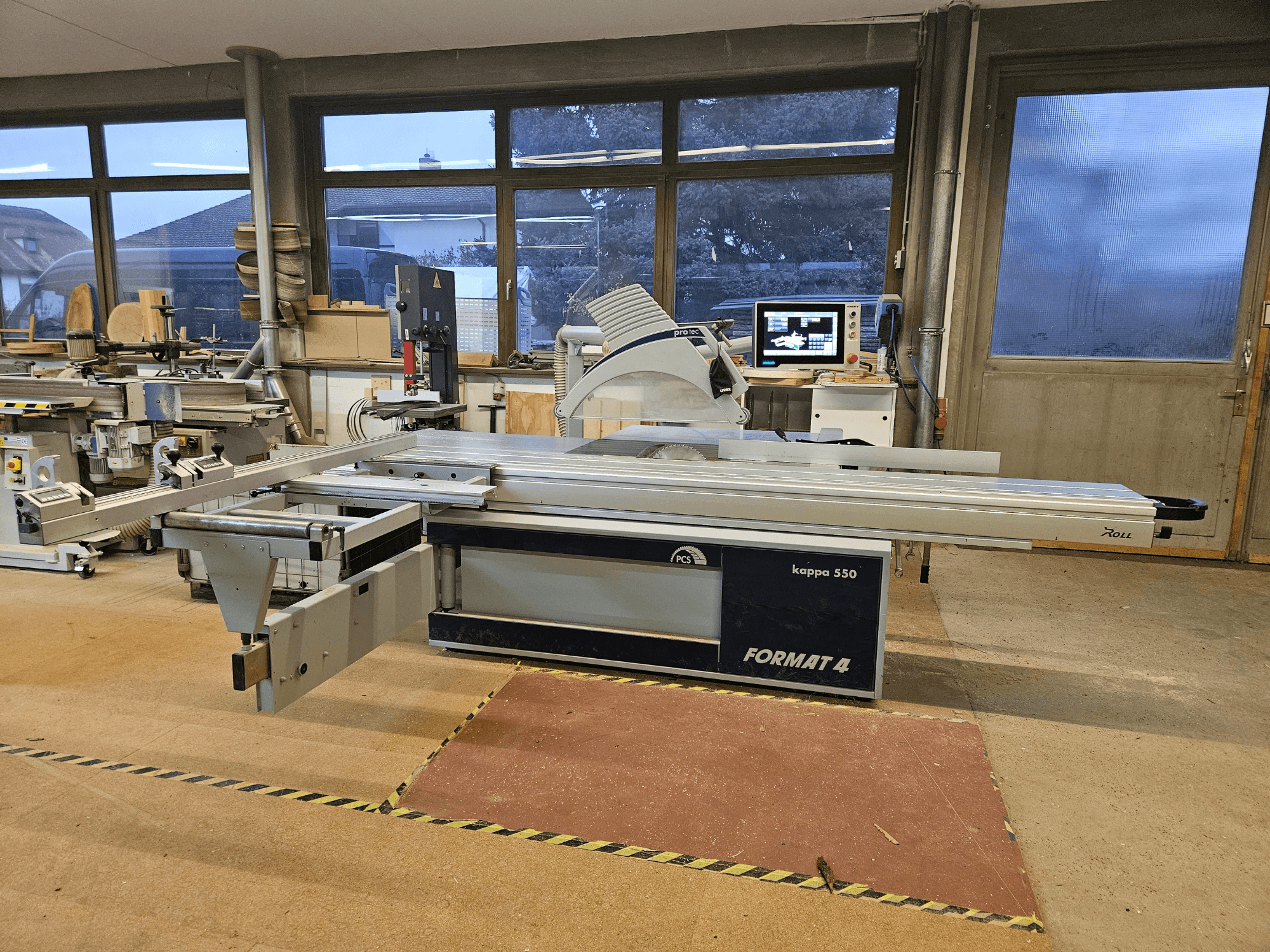 La macchina per il taglio del legno FORMAT4 kappa 550 vista lateralmente, con tavolo scorrevole allungato e monitor integrato.