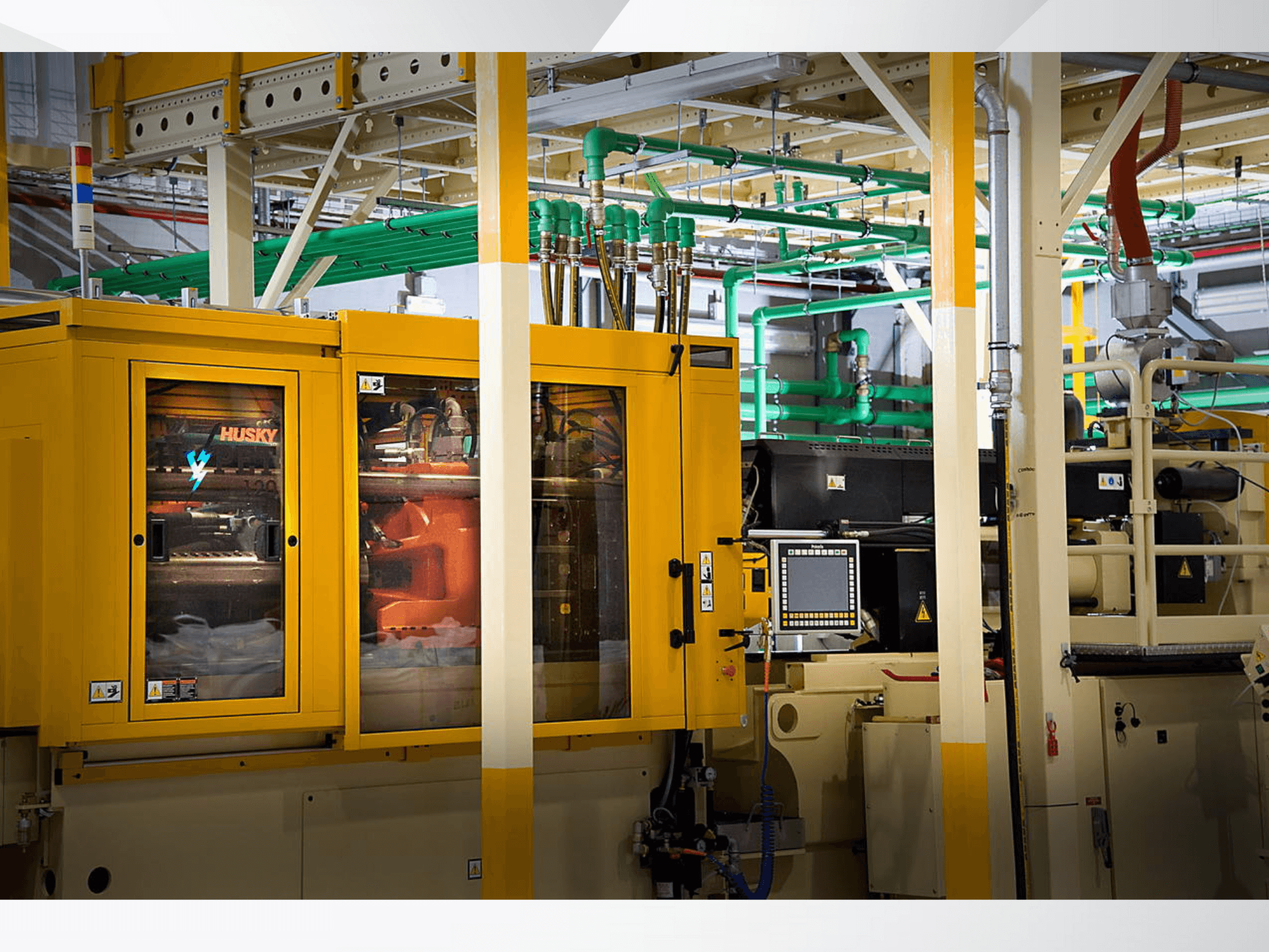 Macchina industriale Husky in giallo, vista frontale che mostra il pannello di controllo e i meccanismi interni sullo sfondo di una fabbrica.