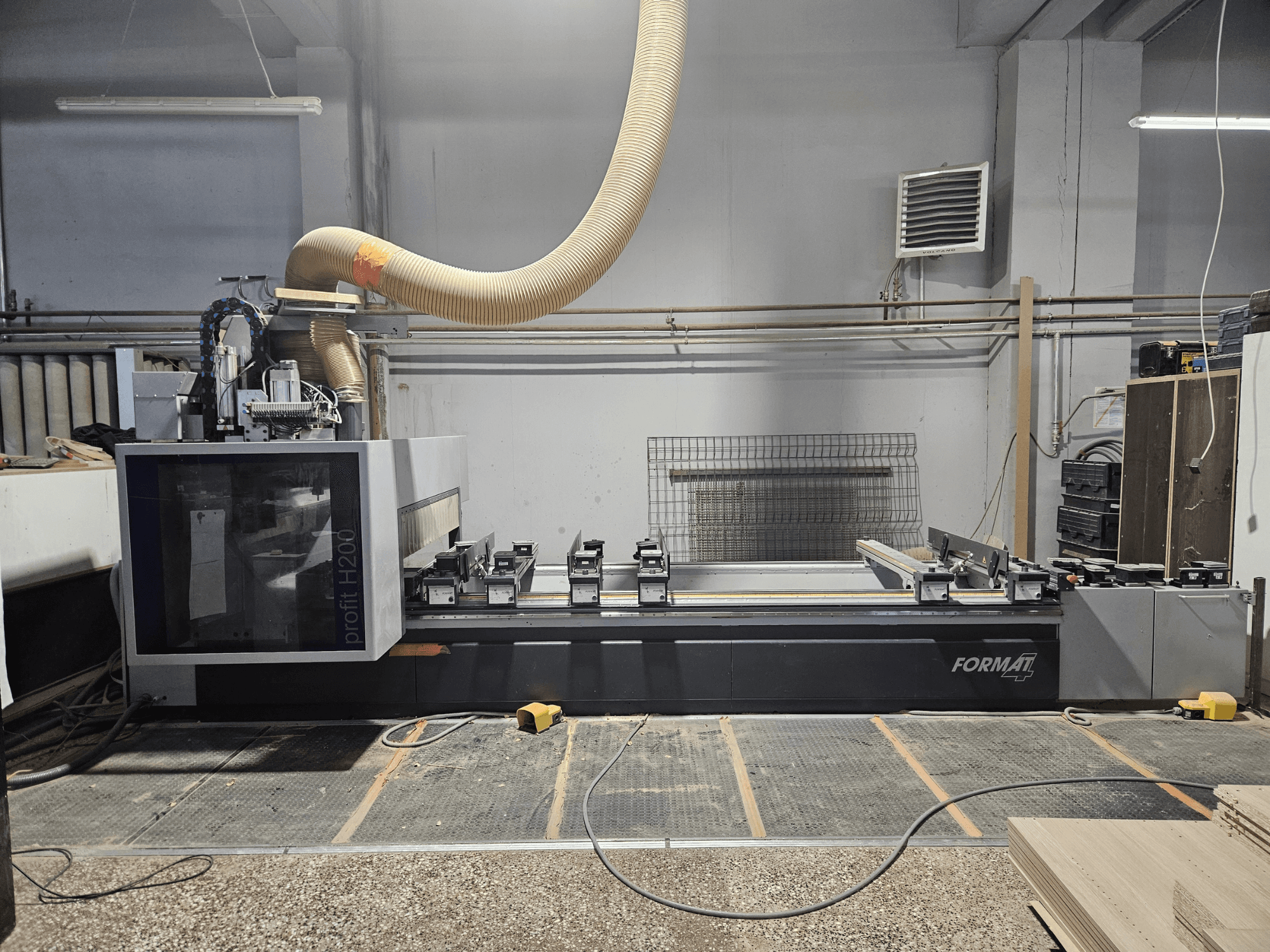 Una macchina CNC FORMAT profit H200 in un'officina, vista laterale, che mostra il piano di lavoro e il sistema di aspirazione della polvere.