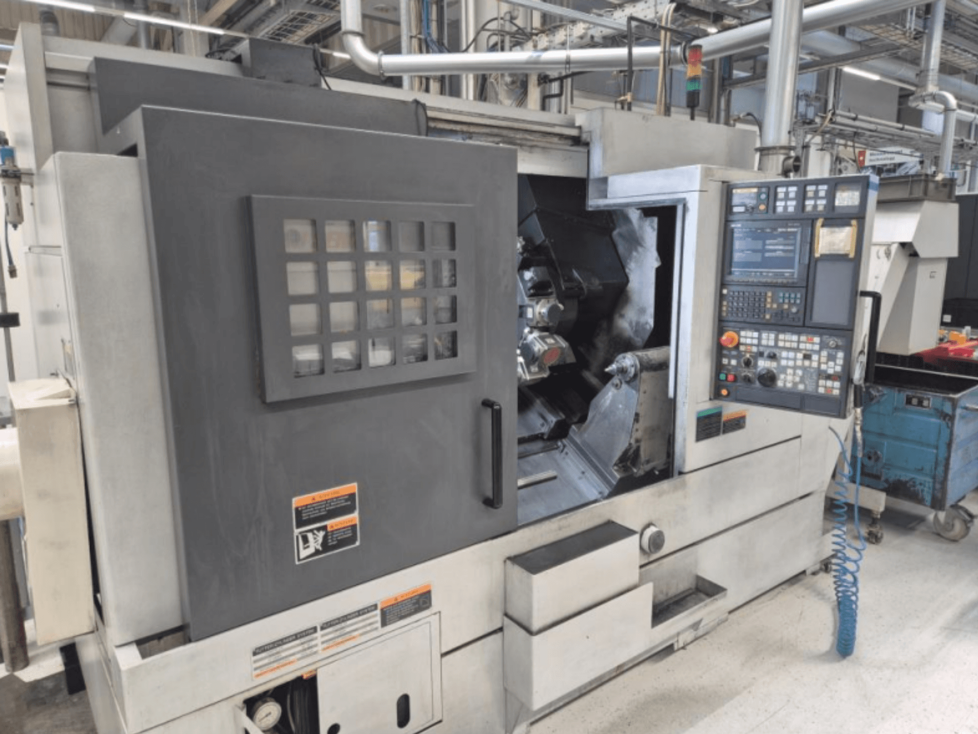 Tornio CNC con pannello di controllo, vista frontale. Area di lavoro visibile e finestra di sicurezza, marca sconosciuta.