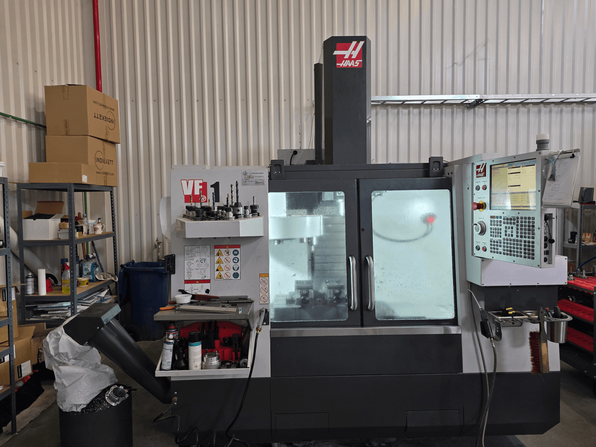 Centro di lavoro verticale HAAS VF 1 in un'officina, vista frontale che mostra il pannello di controllo e l'area di fresatura con gli utensili.