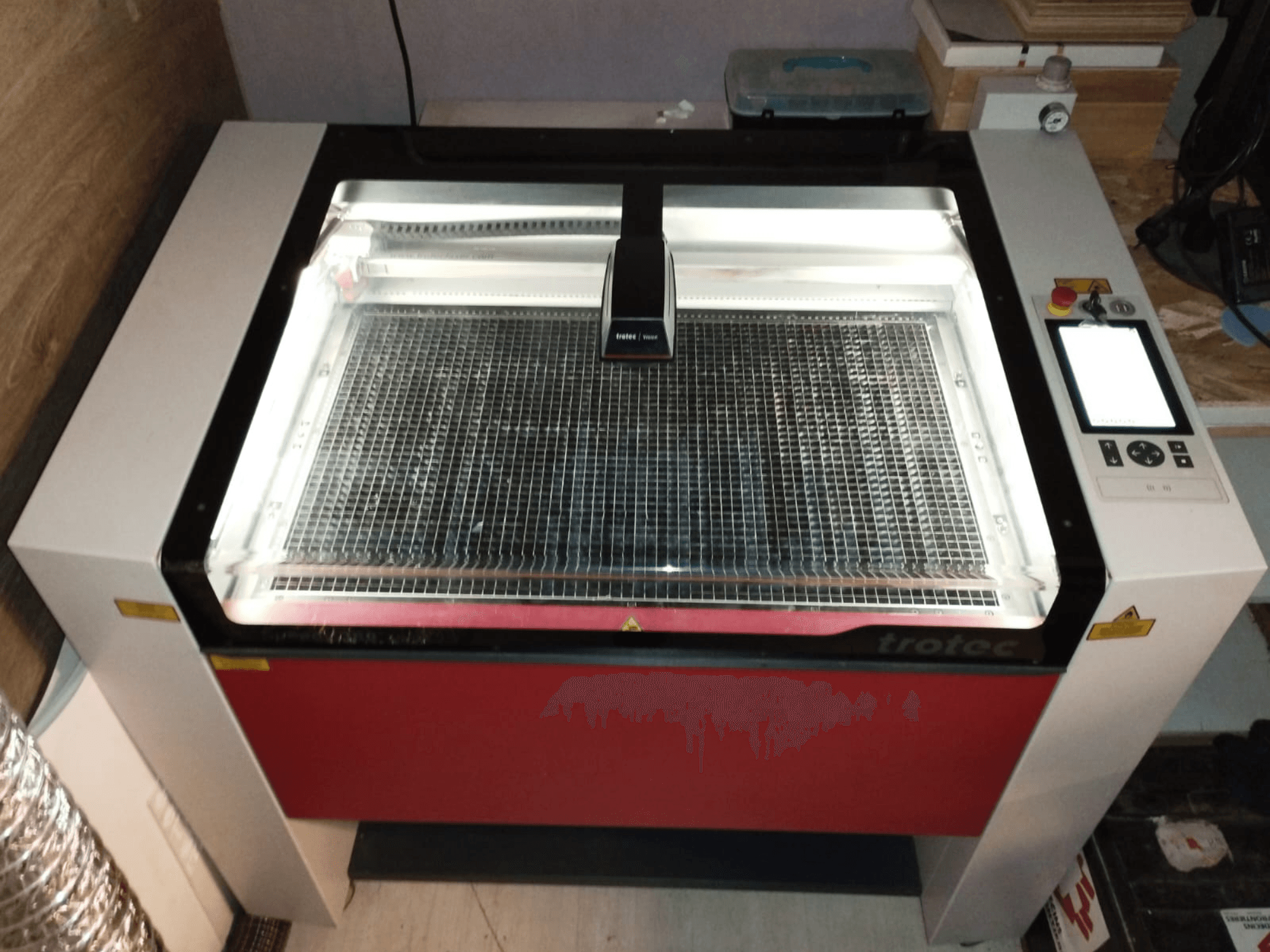 Taglierina laser Trotec con coperchio trasparente, letto a griglia e pannello di controllo sulla destra; vista frontale che mostra il design e le caratteristiche.