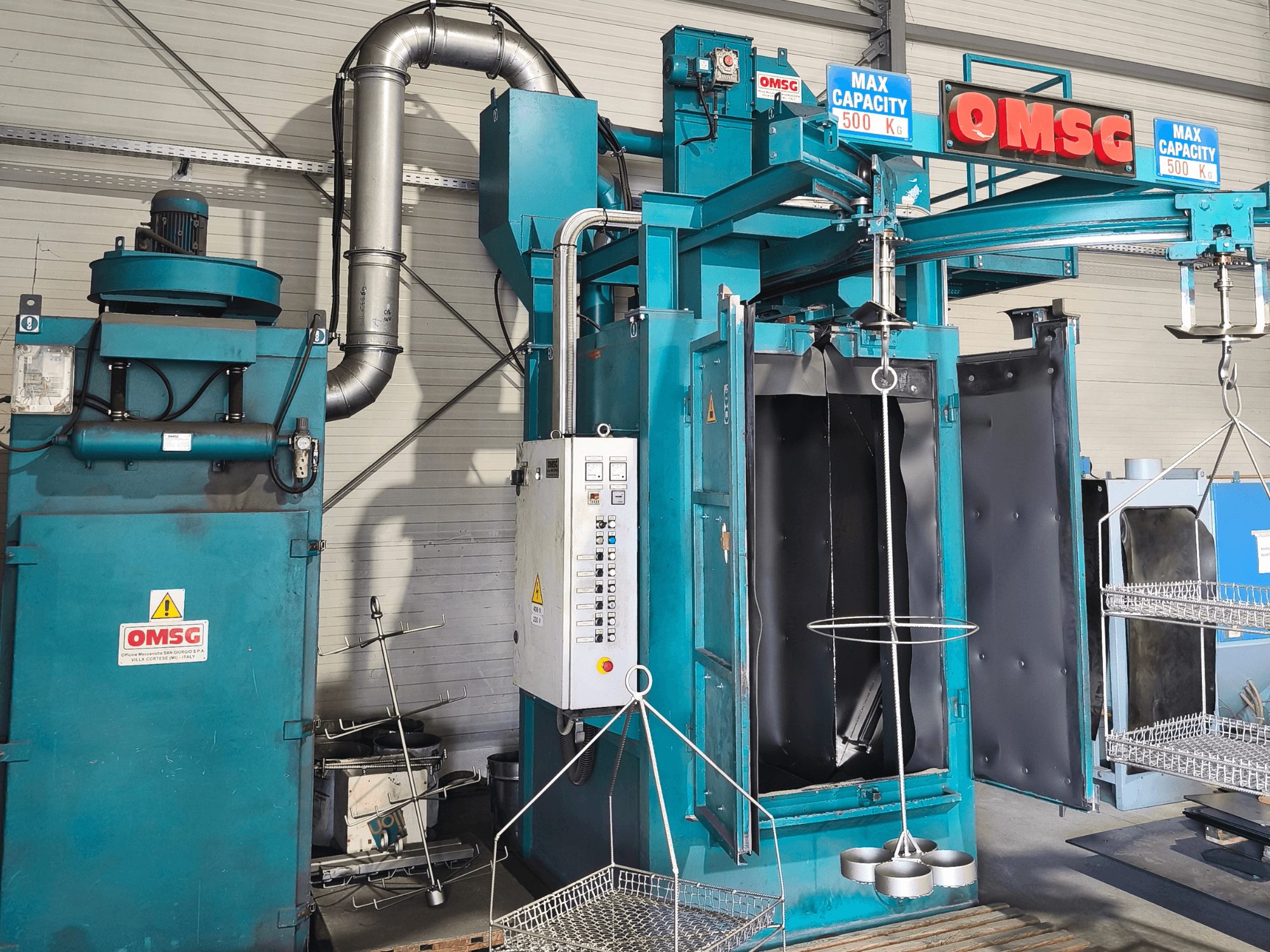 Macchina per la pulizia industriale OMSG con una capacità massima di 500 kg, con pannello di controllo e camera aperta per la pulizia dei pezzi.