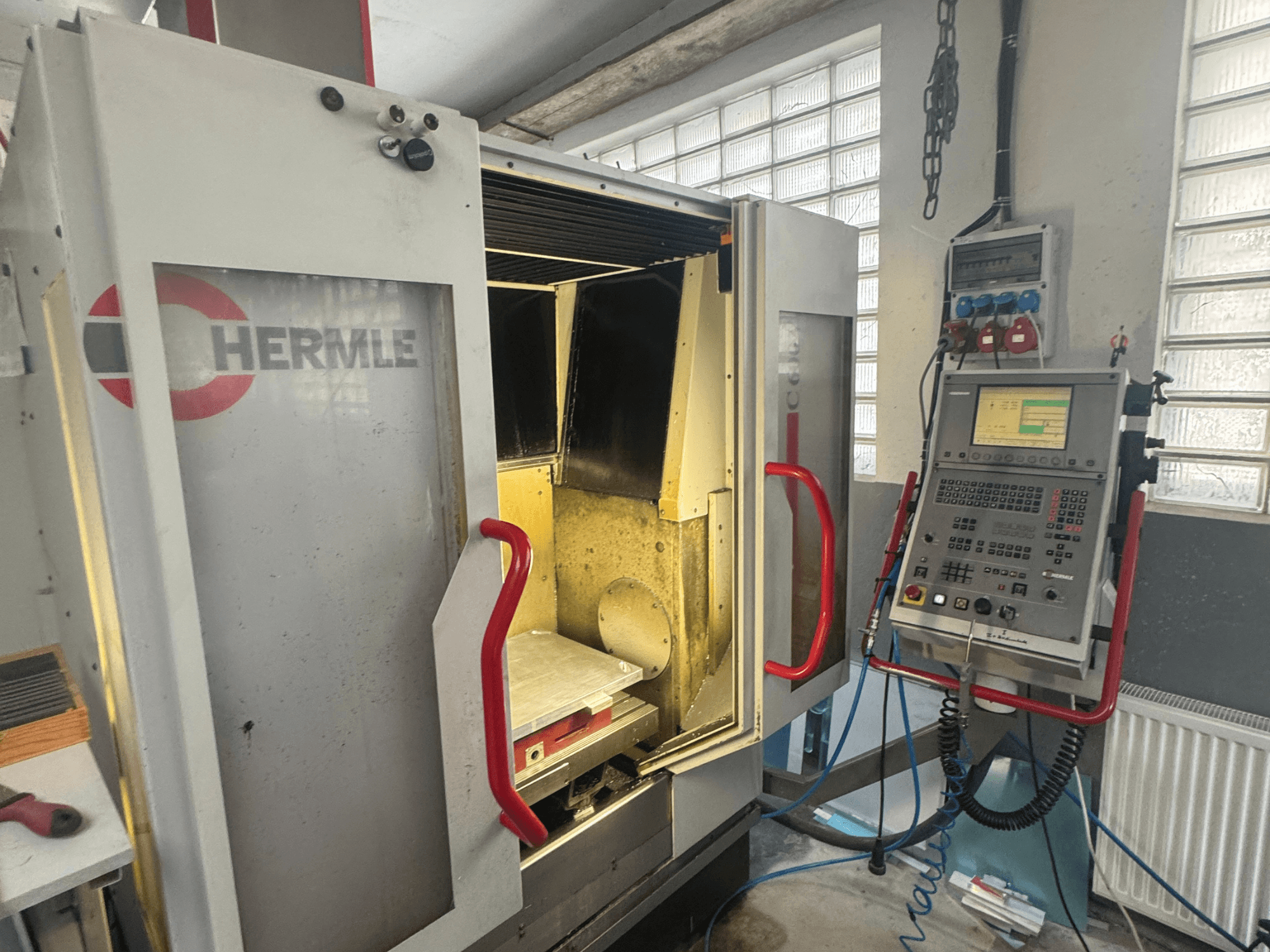 Centro di lavoro verticale HERMLE C600V, vista frontale che mostra la porta aperta, il pannello di controllo e l'area di lavoro interna.