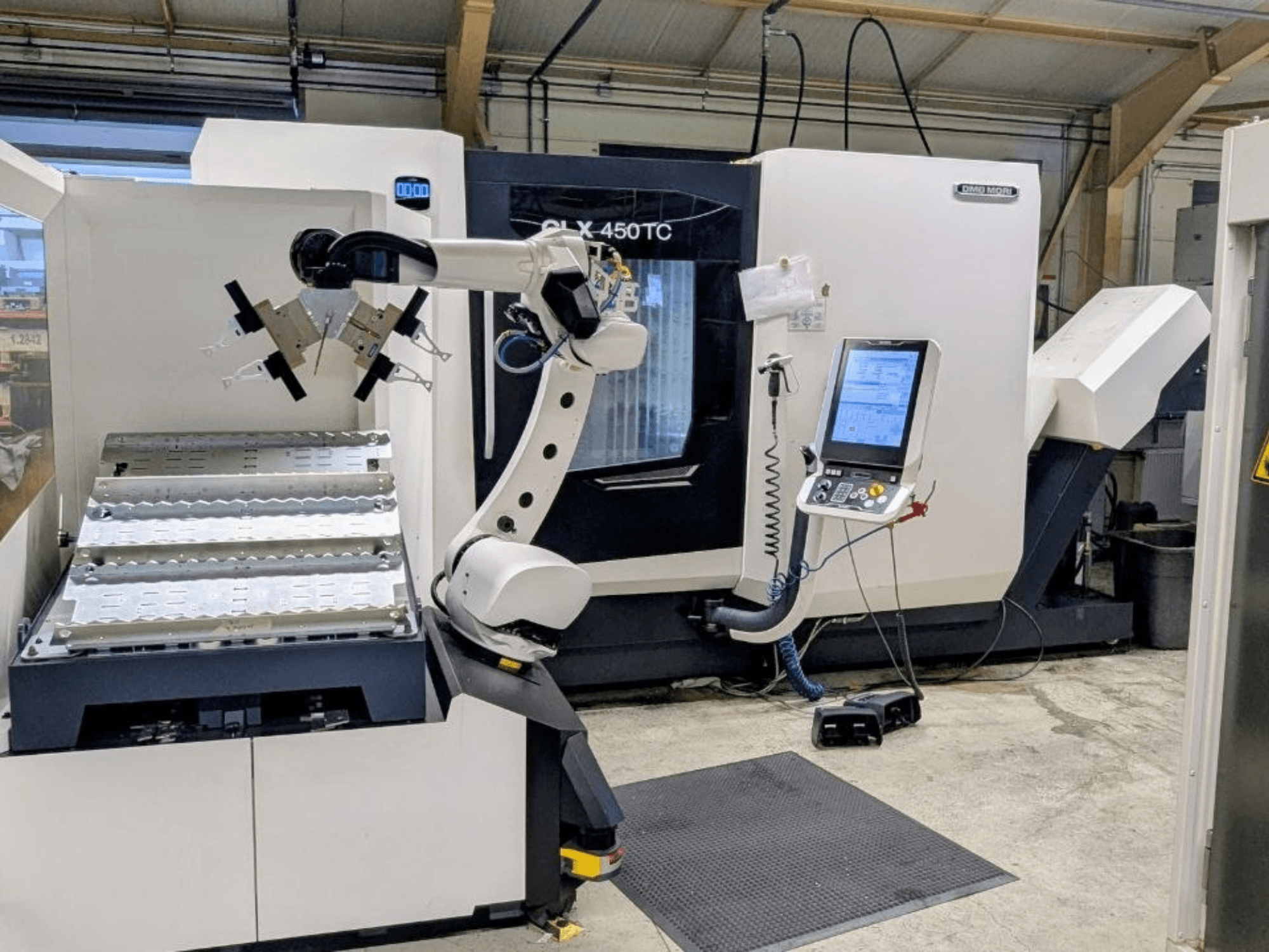 DMG MORI CLX 450 TC con Robo2go, vista frontale, con il braccio robotico e il pannello di controllo accanto alla macchina.