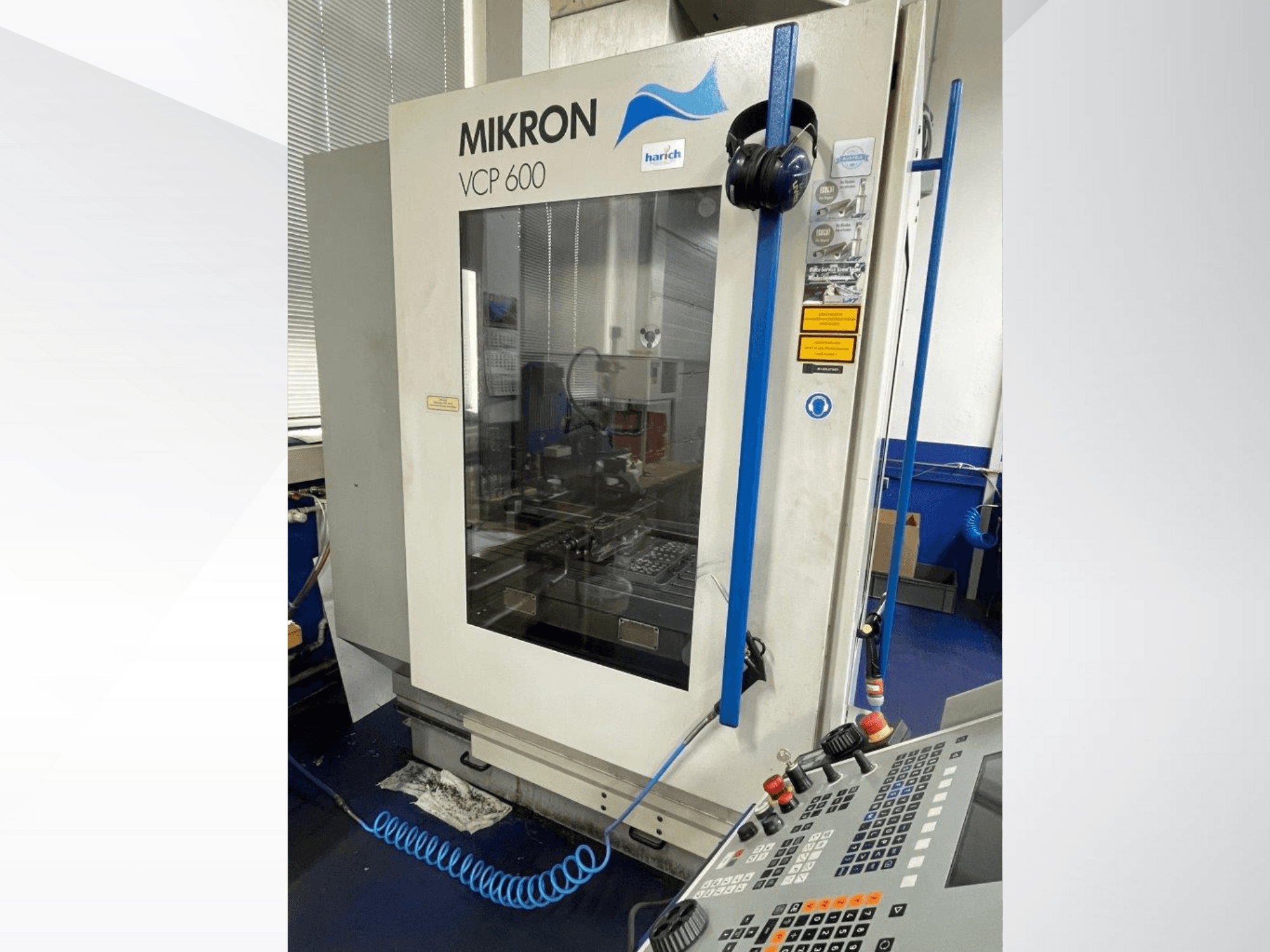 Macchina CNC Mikron VCP 600, vista frontale, con pannello di controllo con pulsanti e area di lavorazione visibile dietro il vetro.