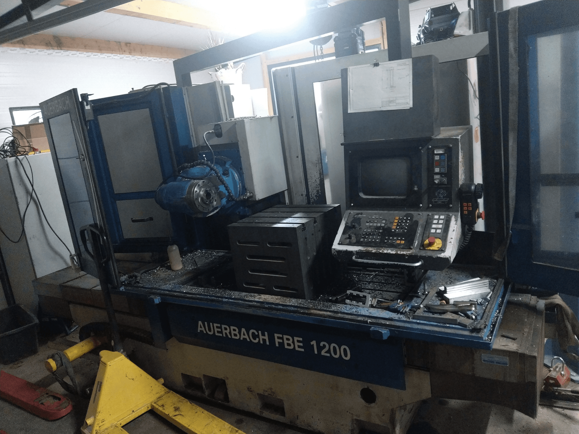 Macchina per la foratura dei metalli Auerbach FBE 1200, vista frontale, che mostra il pannello di controllo, il motore e i trucioli di metallo sulla superficie di lavoro.