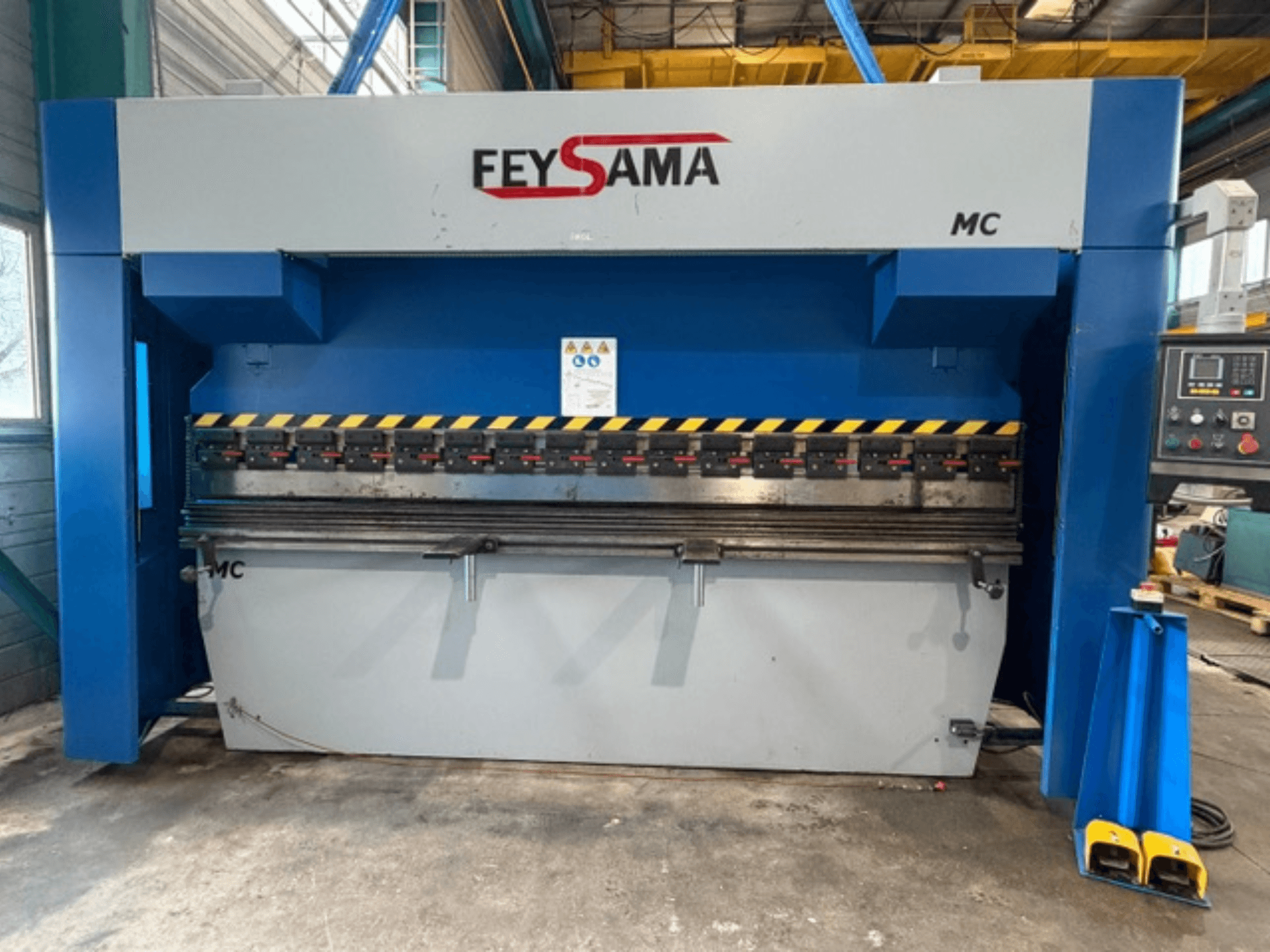 Vista frontale della pressa piegatrice FEYSAMA MCCH 6/3050, con marcature di sicurezza gialle, pannello di controllo a destra e base robusta.