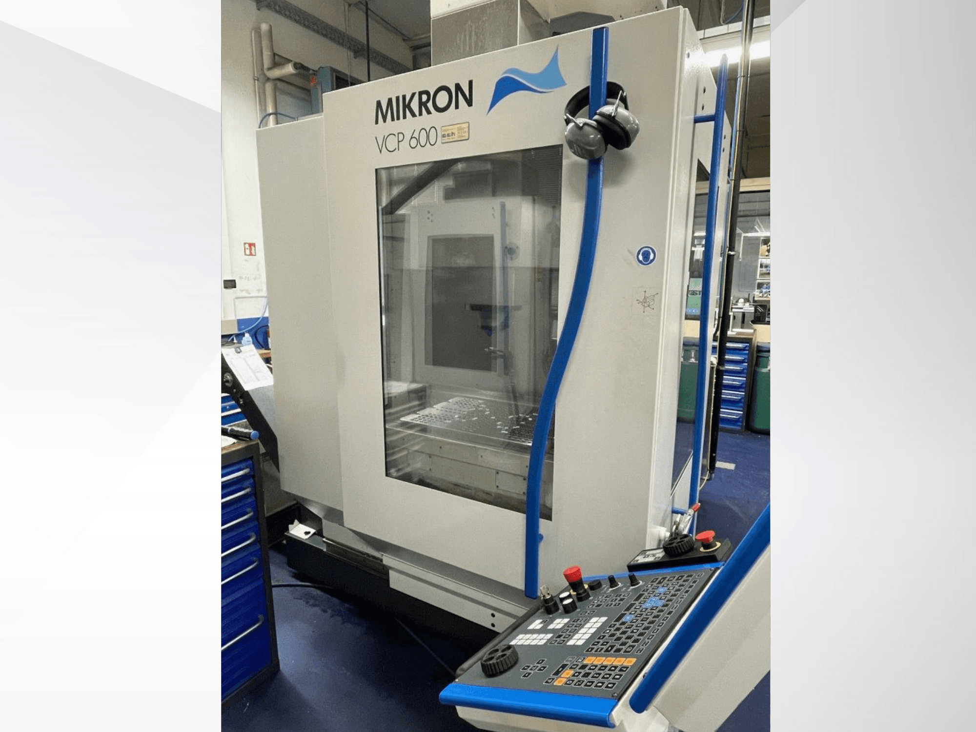 Centro di lavoro Mikron VCP 600 in un'officina, vista frontale, con un pannello di controllo dotato di pulsanti e manopole.