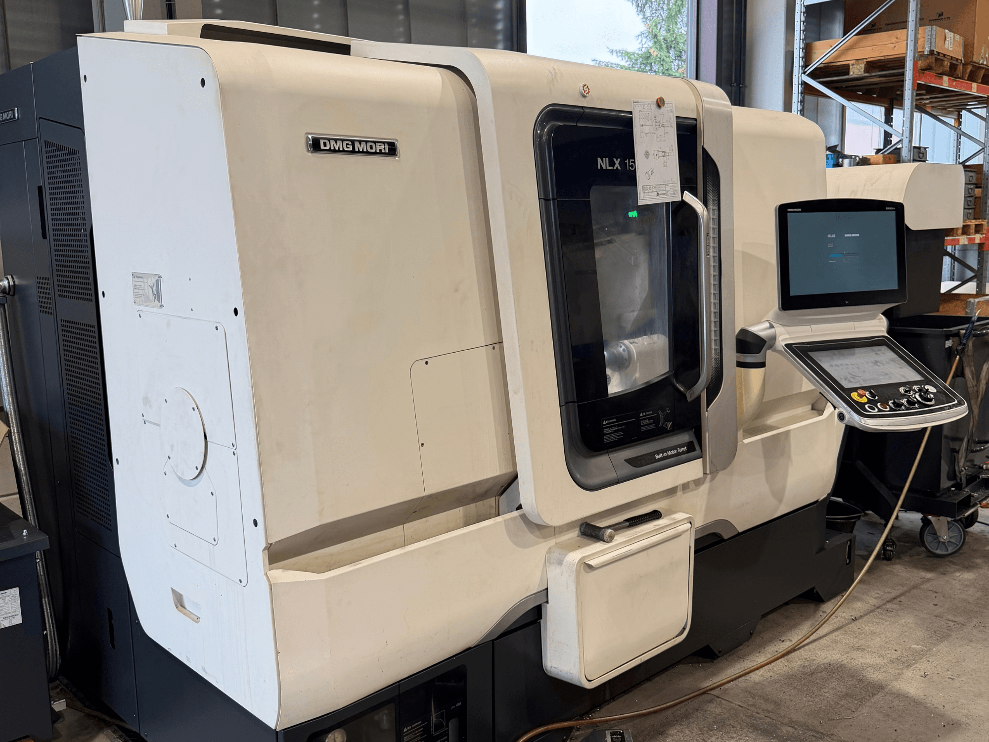 Vista frontale del tornio orizzontale DMG MORI NLX1500MC/500, che mostra il pannello di comando e la zona del mandrino attraverso una copertura trasparente.