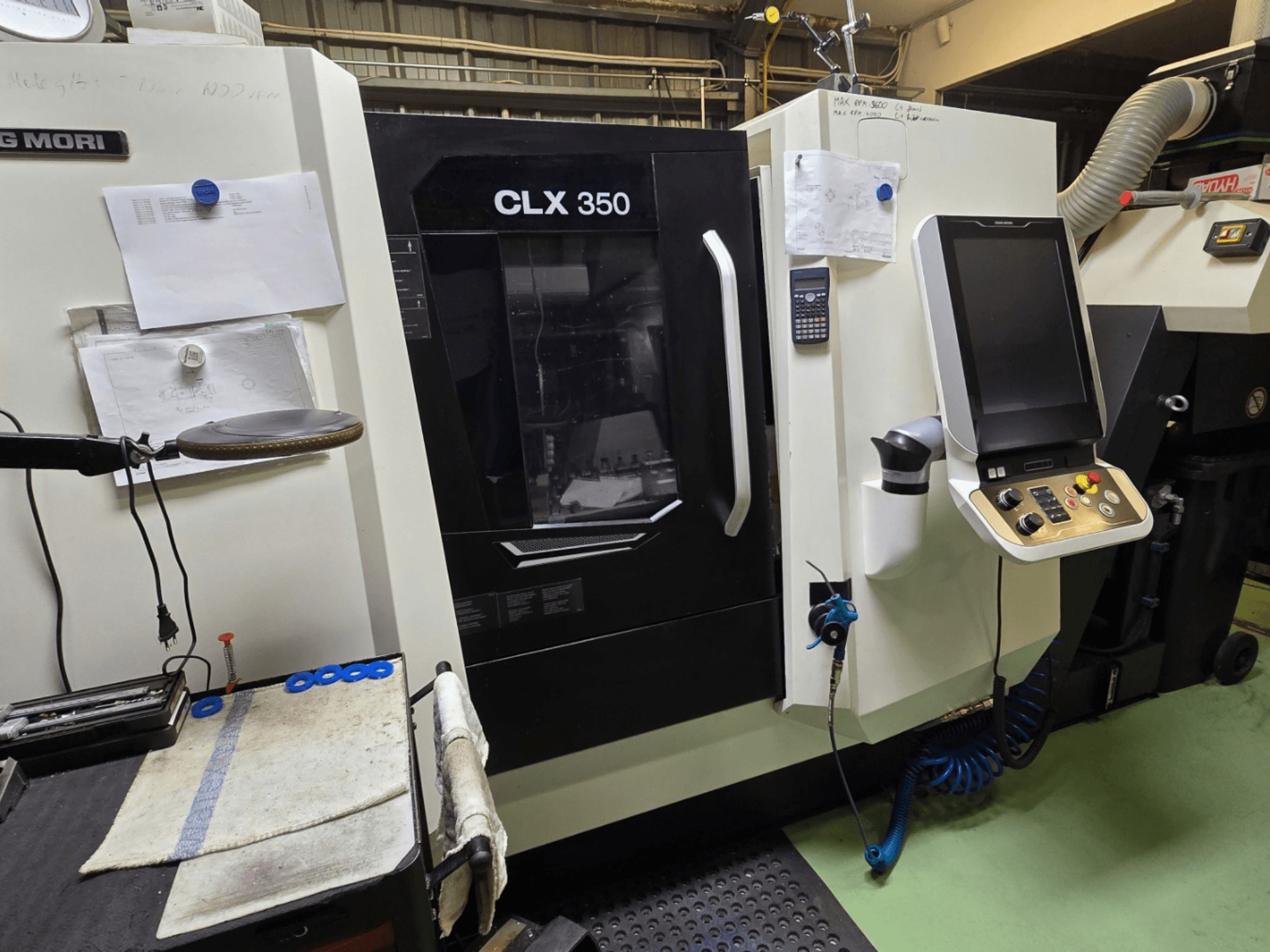 Tornio CNC DMG MORI CLX 350 in un'officina; vista frontale con pannello di controllo, utensili e spazio di lavoro visibili.