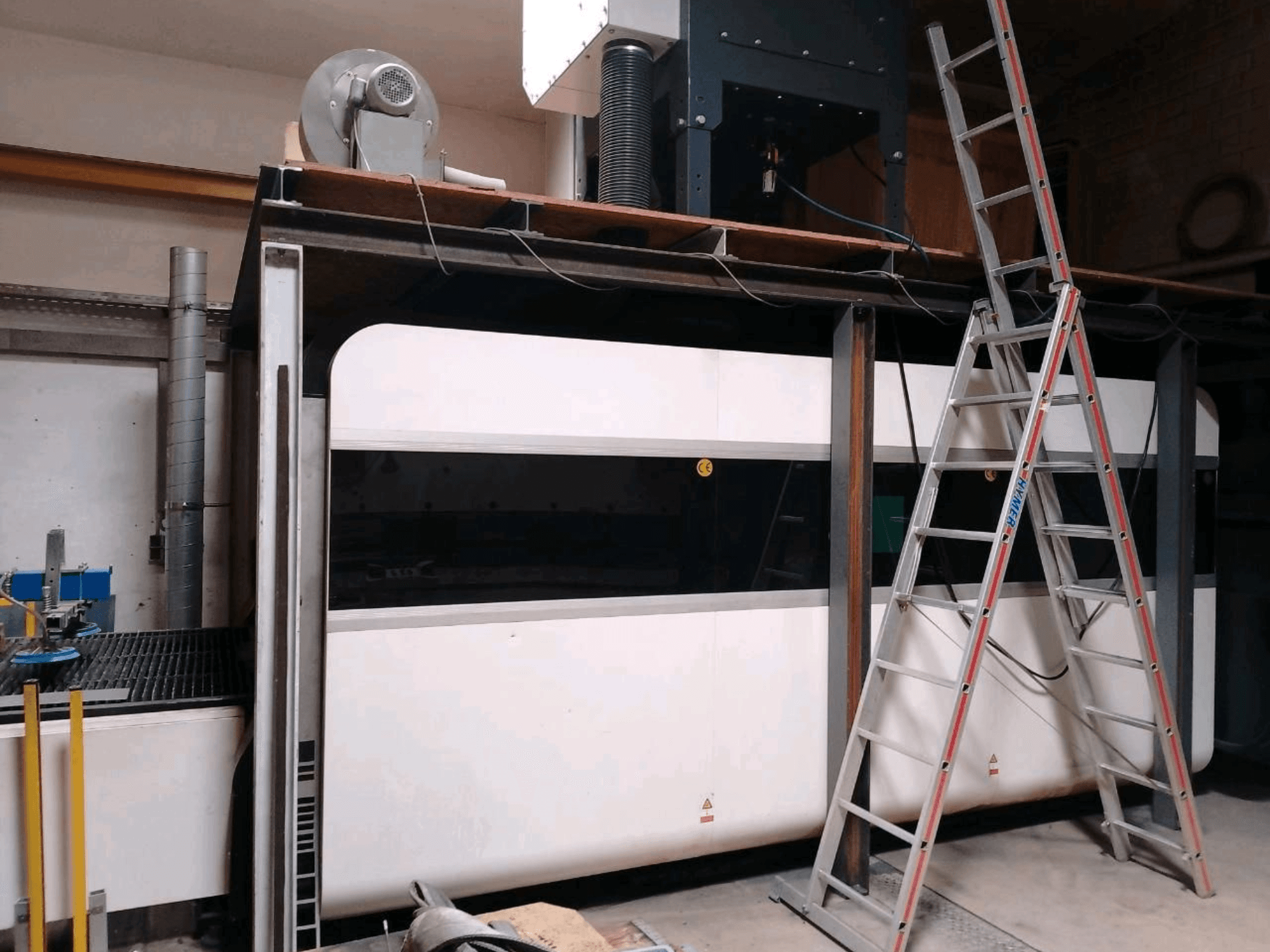 Macchina da taglio a laser a fibra GWEIKE LF3015GA in un'officina, con vista frontale, telaio metallico e scala di accesso.