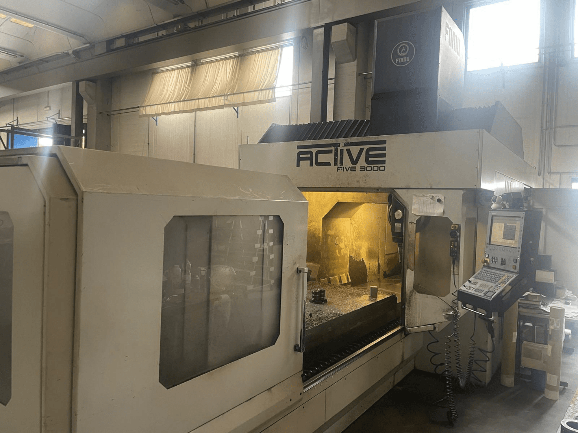 Vista frontale della macchina CNC ACTIVE Five 3000, che mostra il pannello di controllo e l'area di lavoro con il pezzo parzialmente lavorato all'interno.