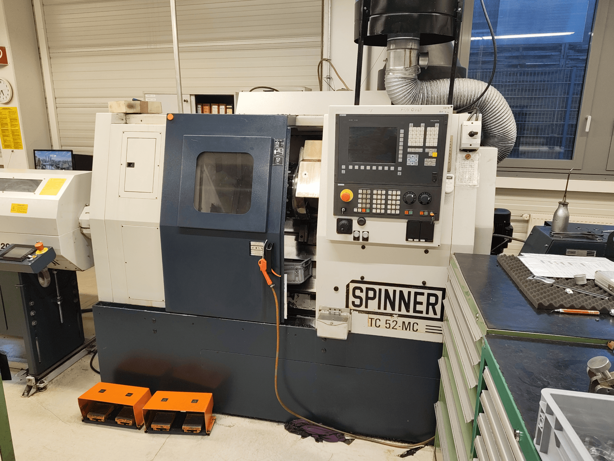 Tornio orizzontale SPINNER TC 52 MC in un'officina, vista frontale, con pannello di controllo, area di lavorazione e dispositivi di sicurezza.