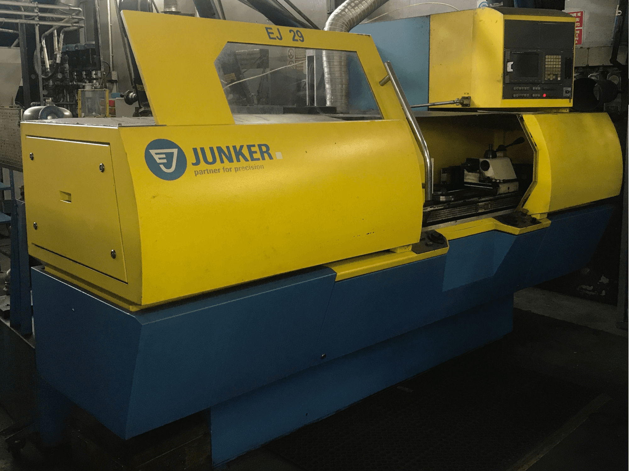 La rettificatrice JUNKER EJ 29, vista frontale, presenta un involucro giallo e blu, un pannello di controllo e componenti interni visibili.