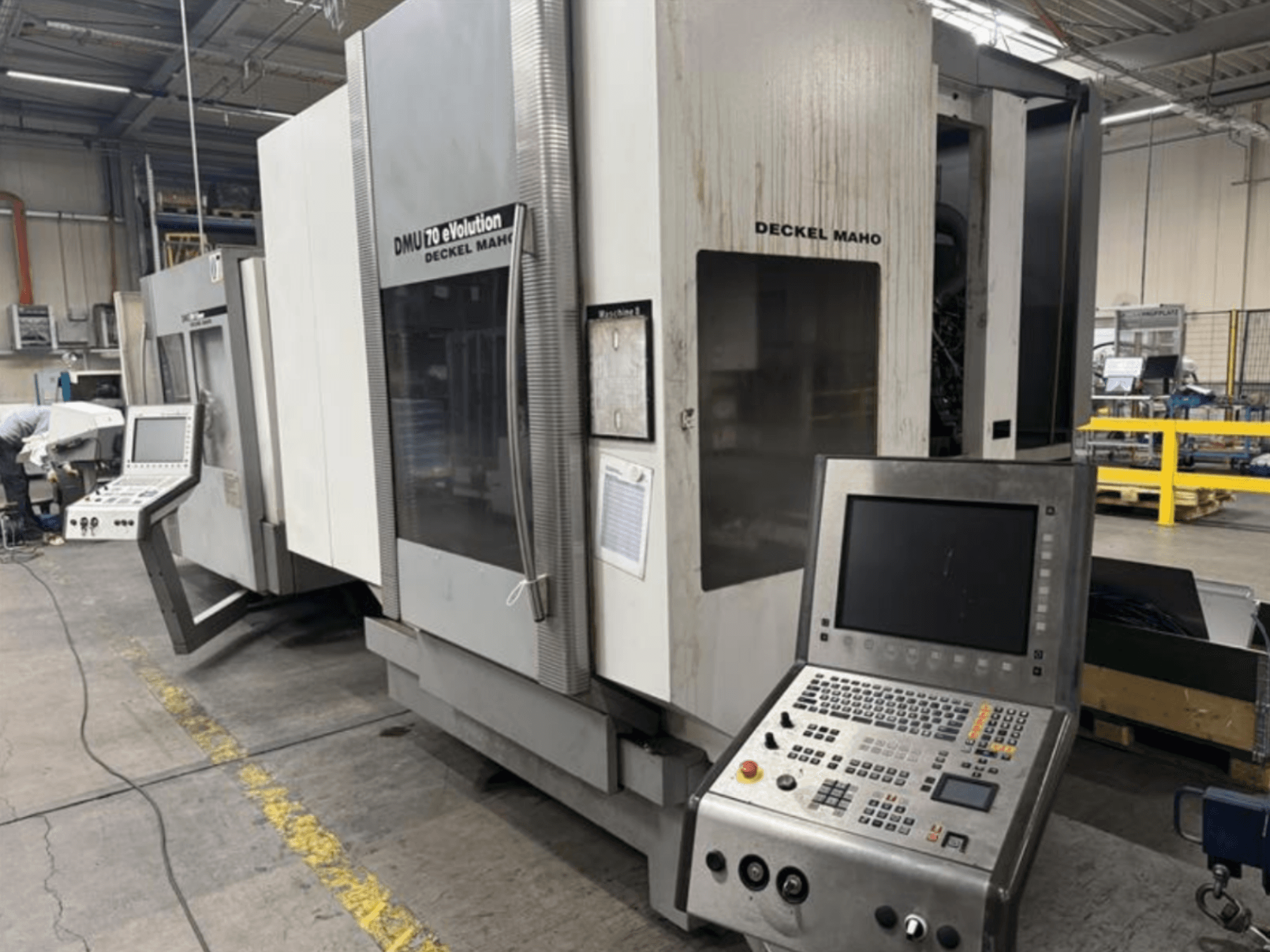 Vista frontale di una macchina CNC Deckel Maho DMU 70 eVOLUTION con pannello di controllo, situata in uno stabilimento di produzione.
